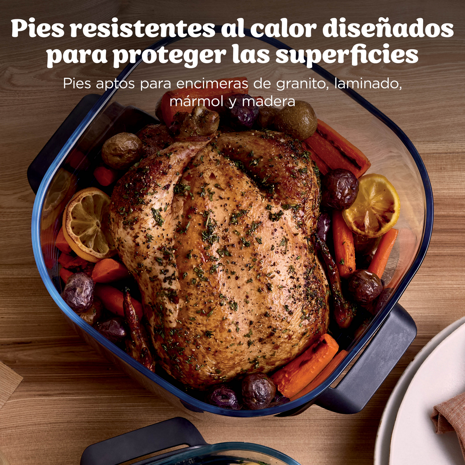 Un pollo asado con verduras en una fuente de vidrio sobre una mesa de madera.