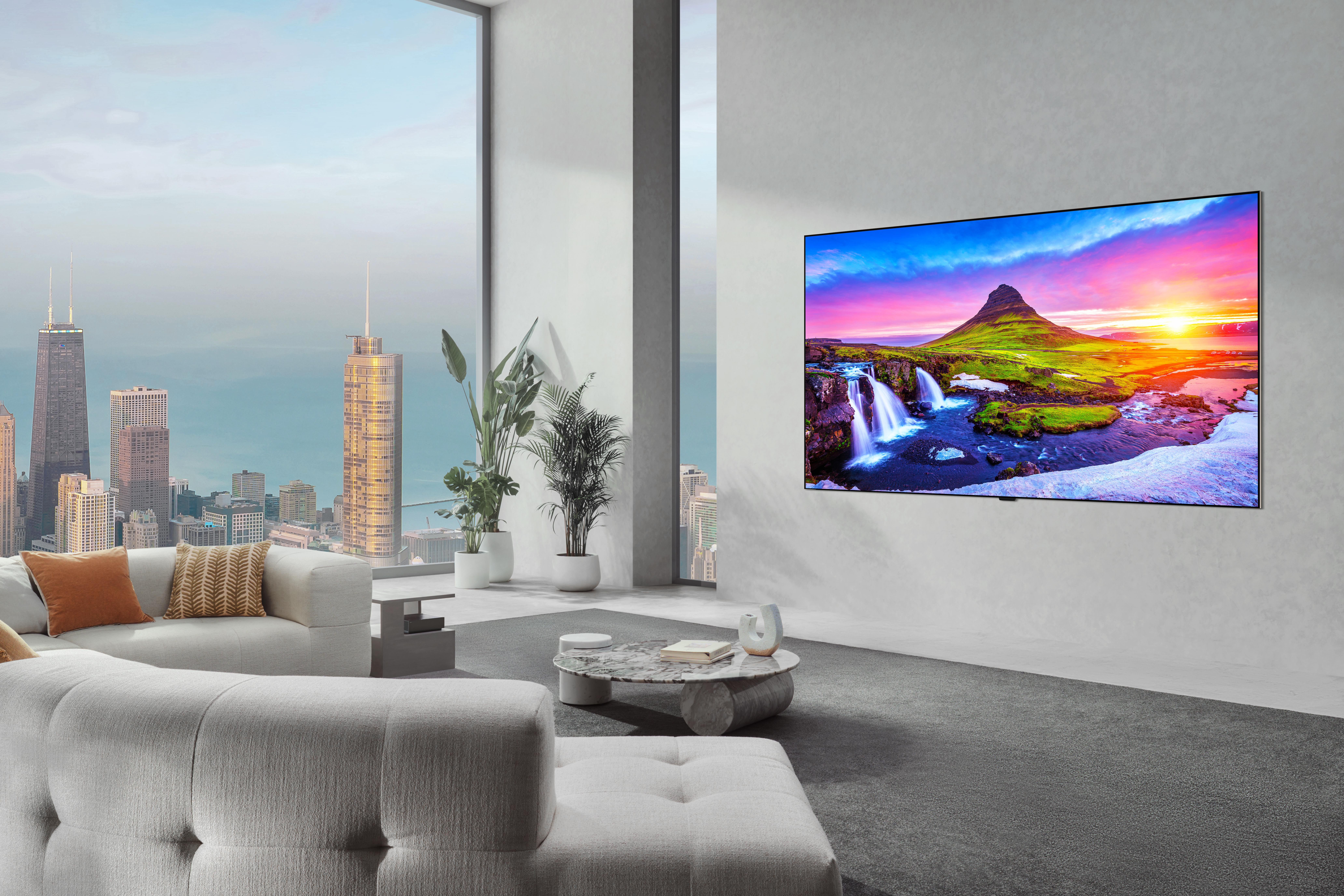Modernes Wohnzimmer mit großem Fenster und Blick auf die Stadtsilhouette. TV zeigt einen Wasserfall.