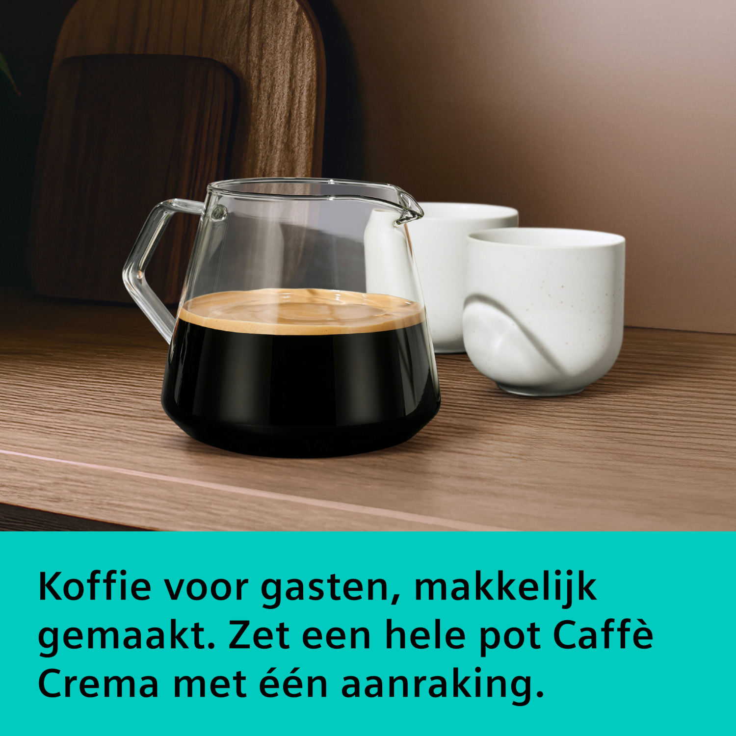 Glass coffee pot with coffee next to two cups on a wooden shelf.
