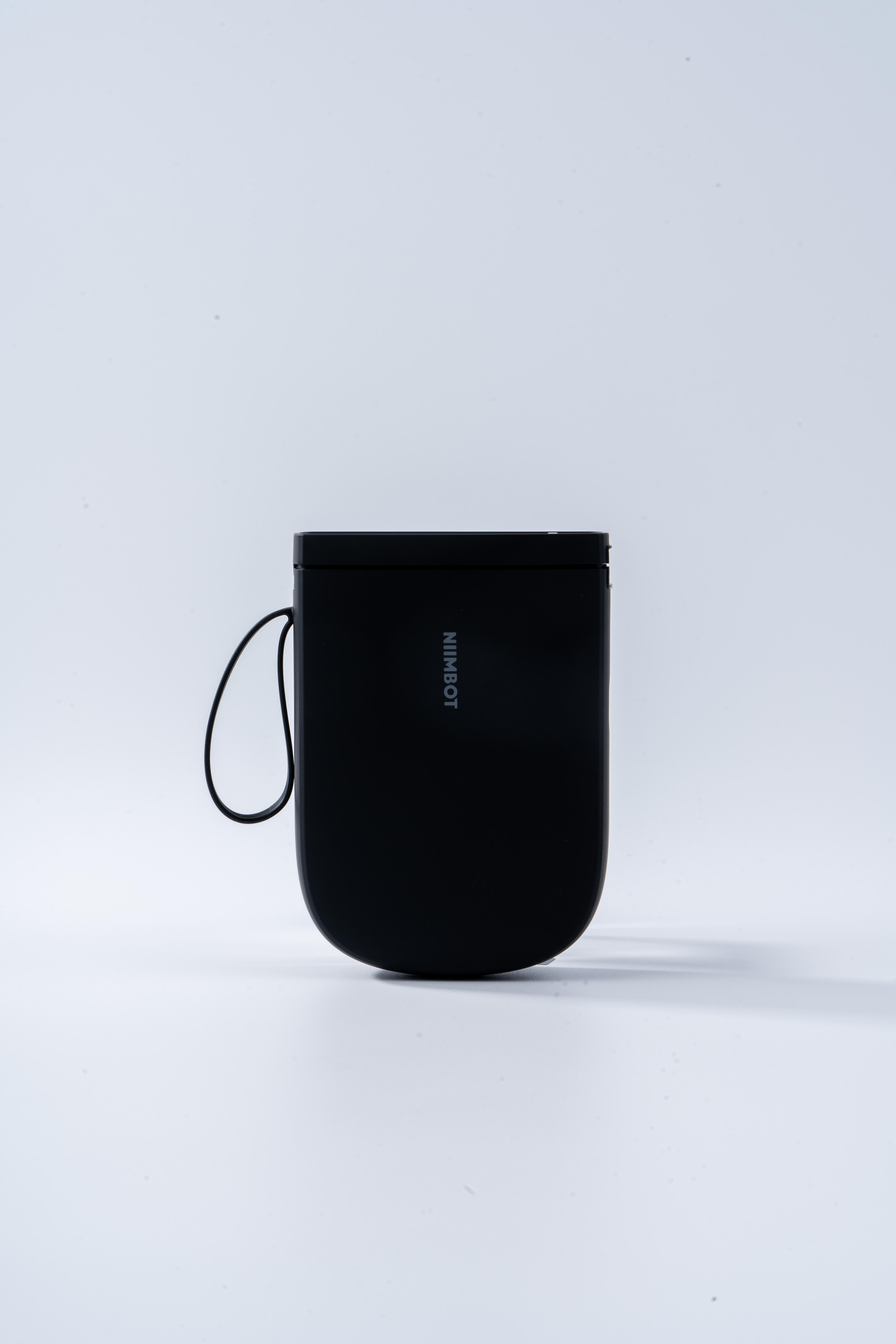 Ein schwarzes NIIMBOT-Gerät mit einer Schlaufe auf weißem Hintergrund.