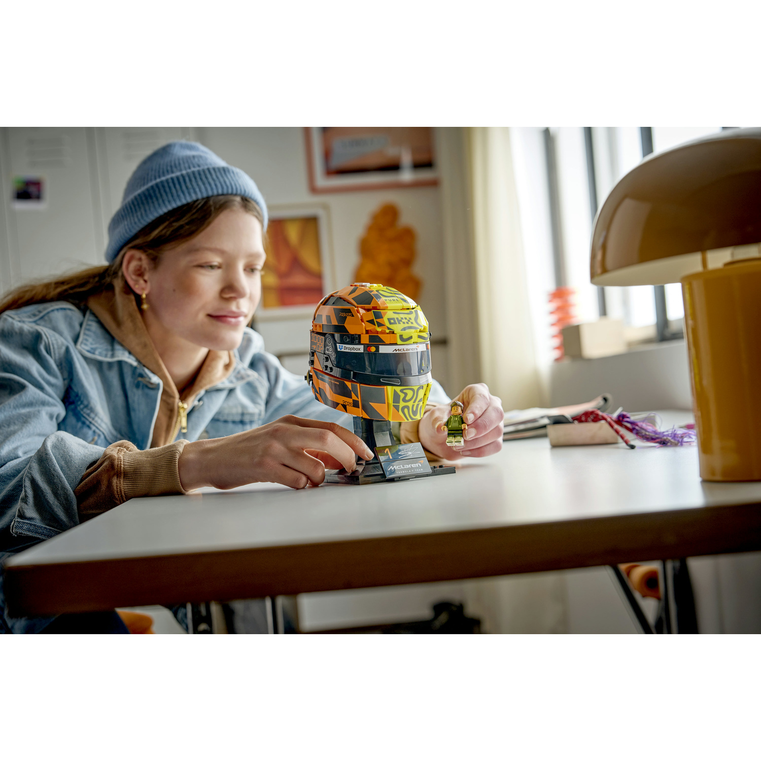 Una ragazza con berretto blu costruisce un casco Lego con una piccola figura Lego.