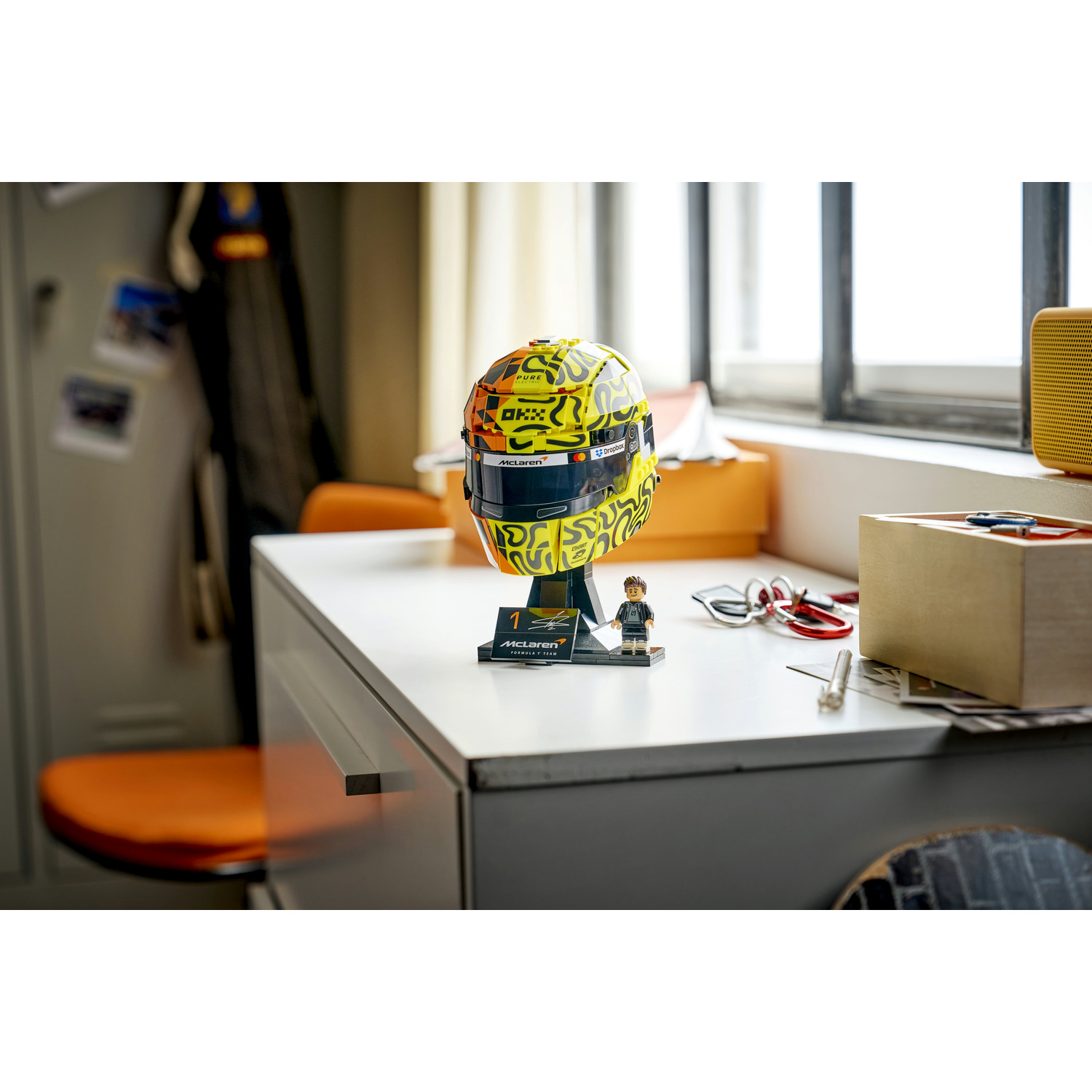 Un casco modello McLaren F1 giallo e nero su una scrivania con una minifigure.