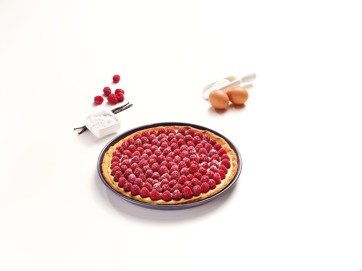 Himbeertarte auf einem Teller mit Eiern, Vanille und Puderzucker.