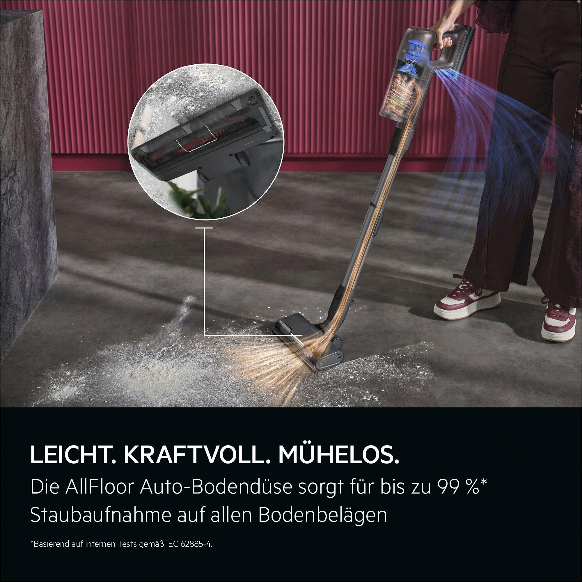 Ein Handstaubsauger saugt Staub von einem grauen Boden auf. Nahaufnahme der Bürste.