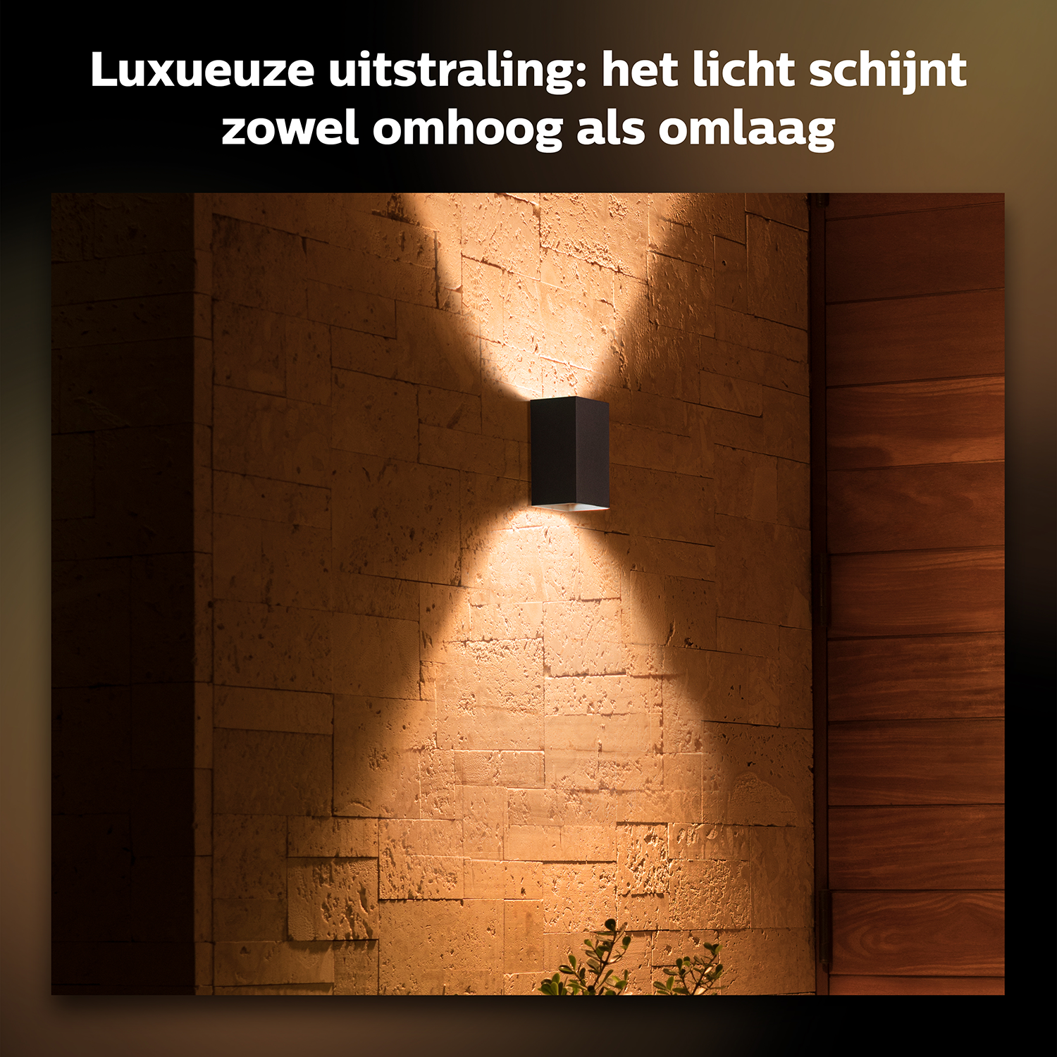 Een rechthoekige wandlamp verlicht een stenen muur.