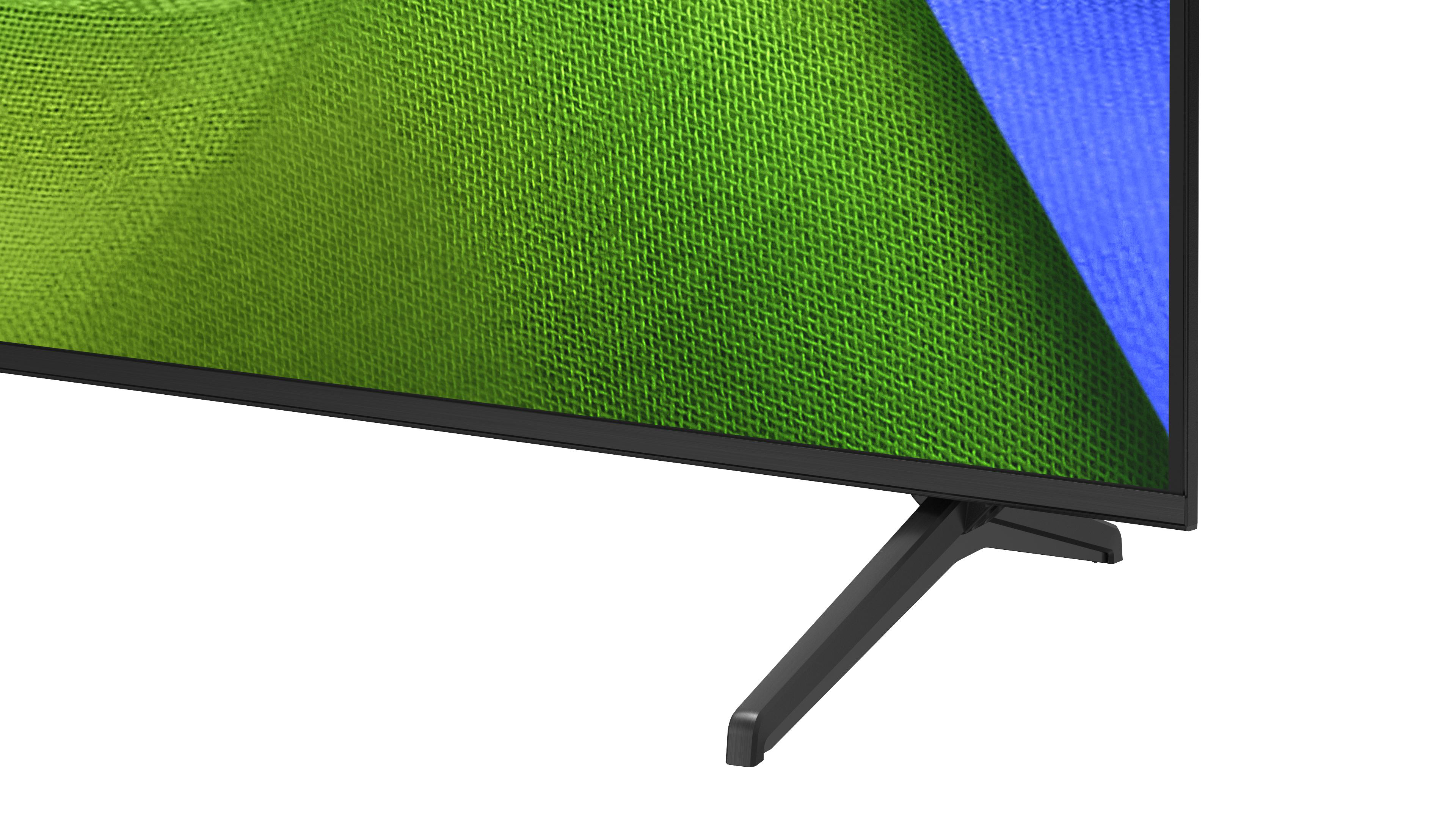 Nahaufnahme eines Fernsehers mit schwarzem Rahmen und einem Standfuß. Die Leinwand zeigt grüne und blaue Muster.