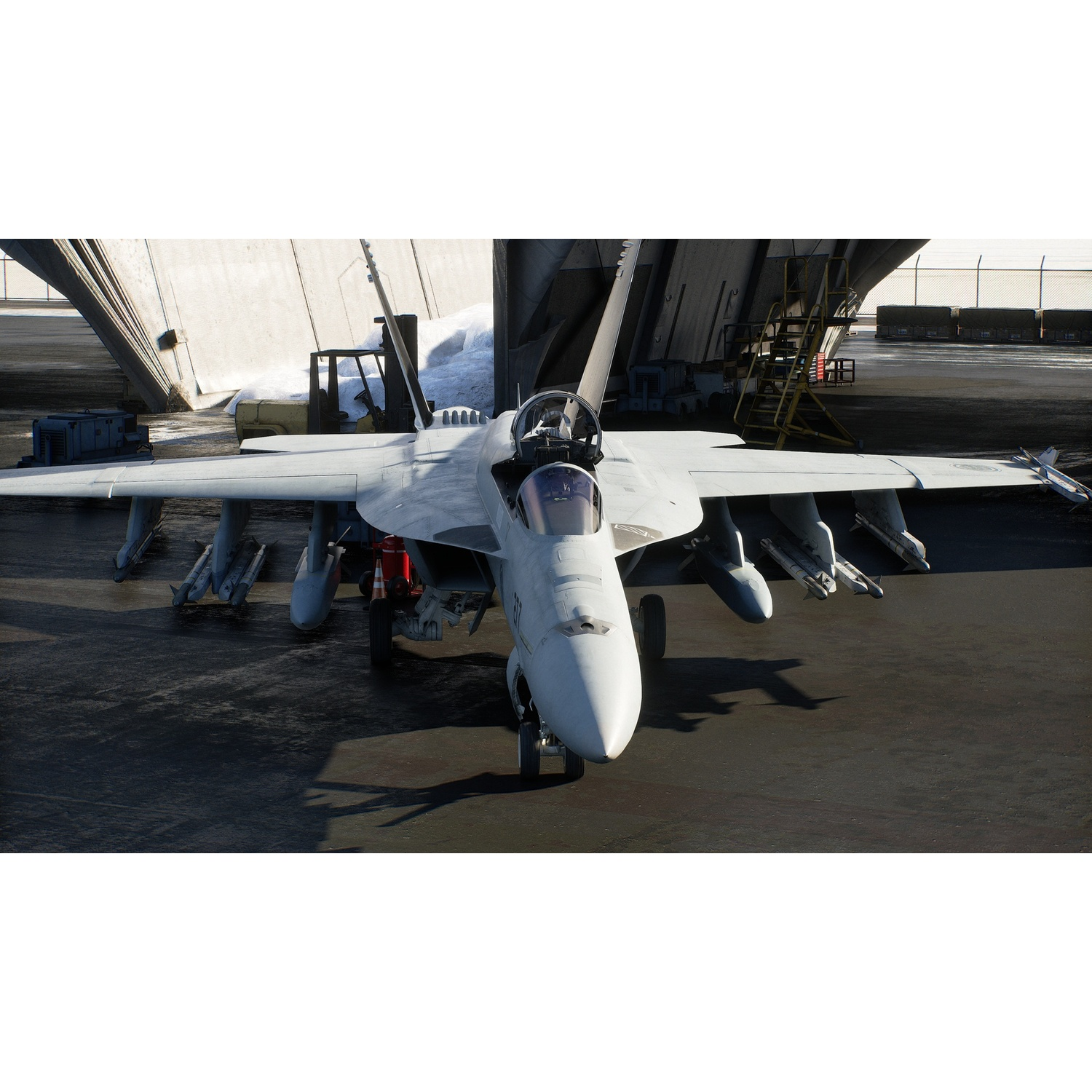 Un avion de chasse gris est garé sur le pont d'un porte-avions avec un grand hangar en arrière-plan.