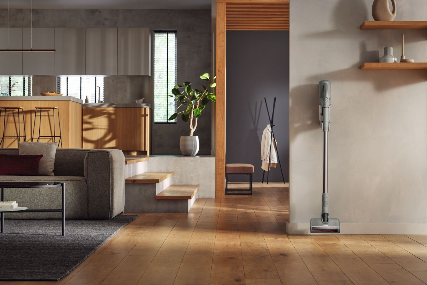 Ein moderner Wohnraum mit Sofa, Kamin, Küche und einem Staubsauger an der Wand.