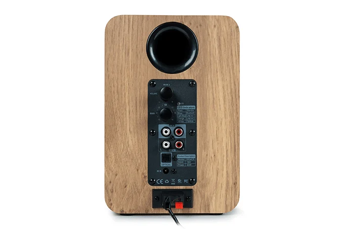 Parte trasera de un altavoz de madera con puertos, perillas y un tubo bass reflex.
