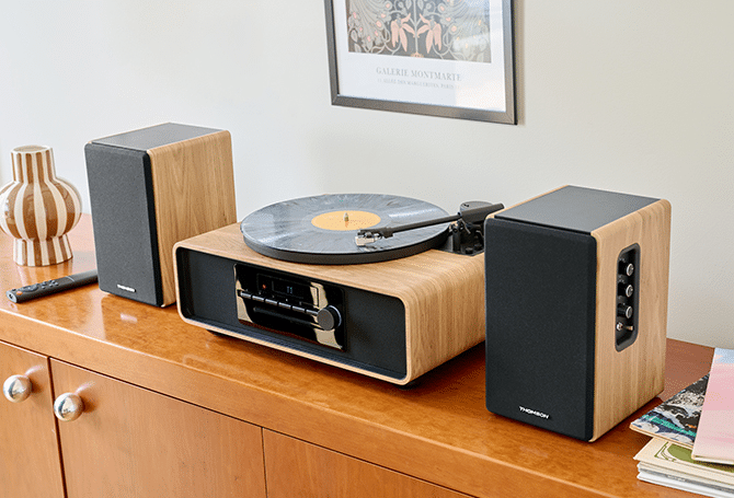 Un tocadiscos con dos altavoces y un jarrón en un mueble de madera.