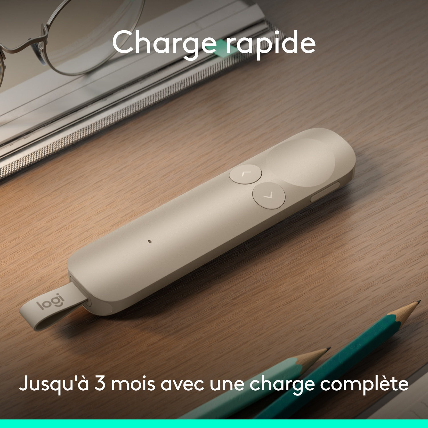 Un présentateur Logitech sur un bureau en bois avec des lunettes et des crayons.