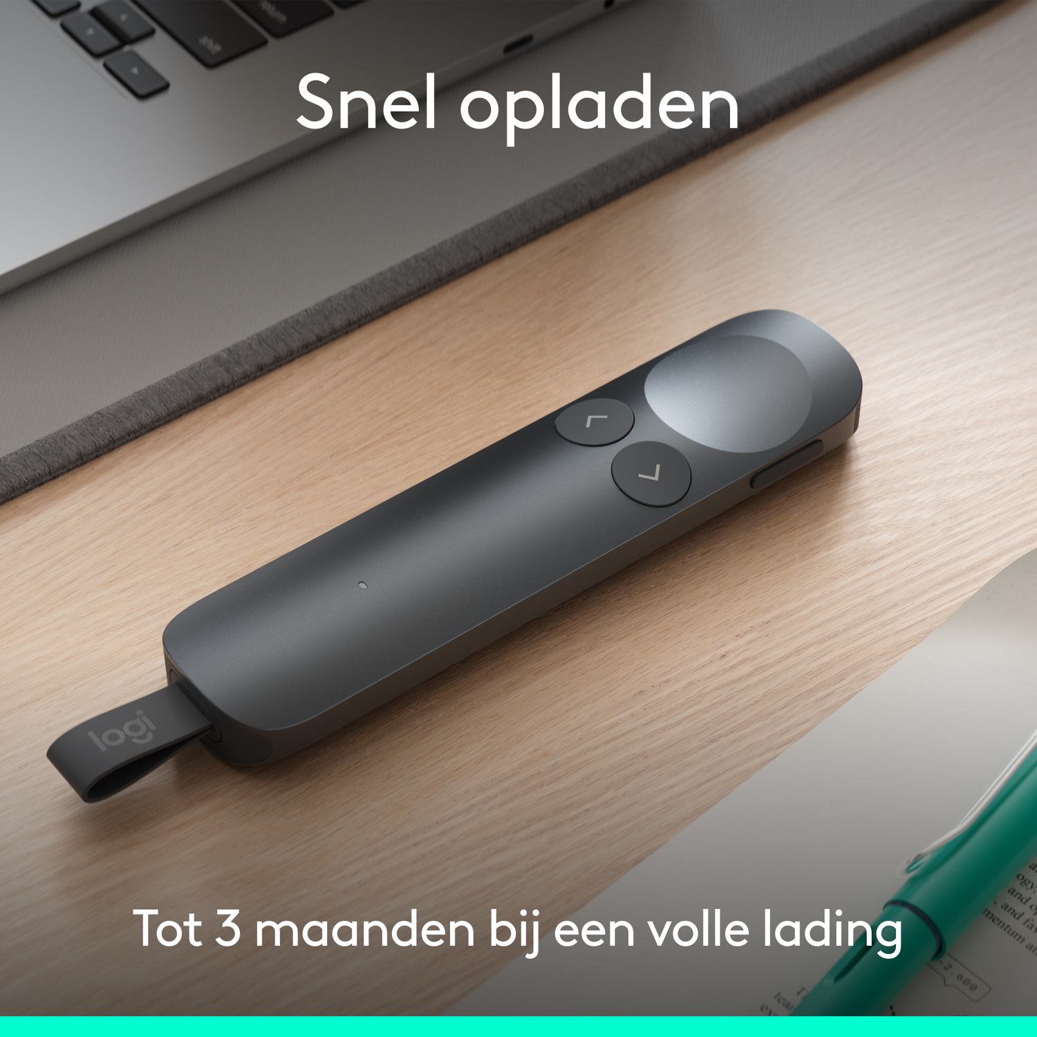 Een grijze Logitech presenter ligt op een houten bureau naast een laptop.