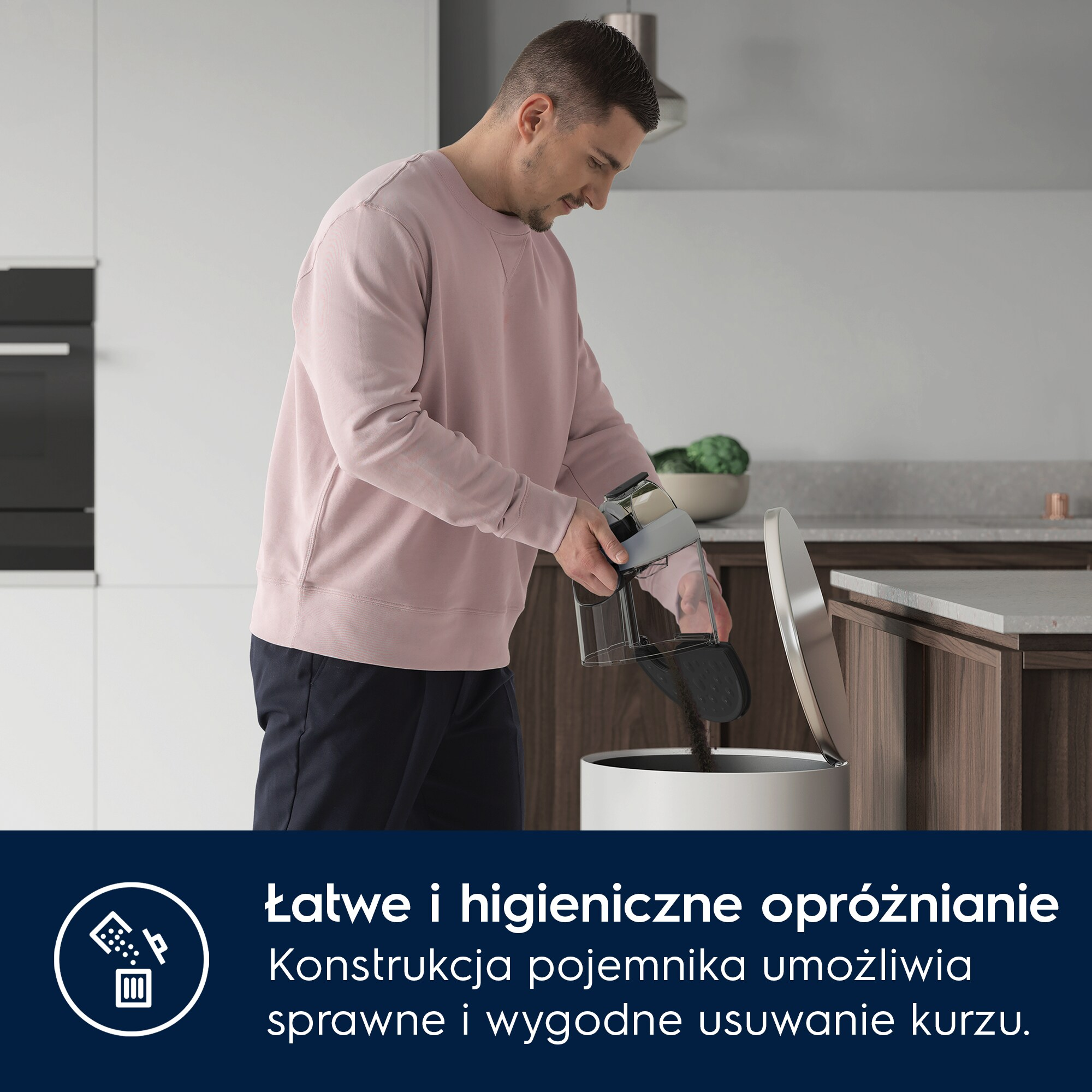 Mężczyzna opróżnia pojemnik odkurzacza do białego kosza w nowoczesnej kuchni.
