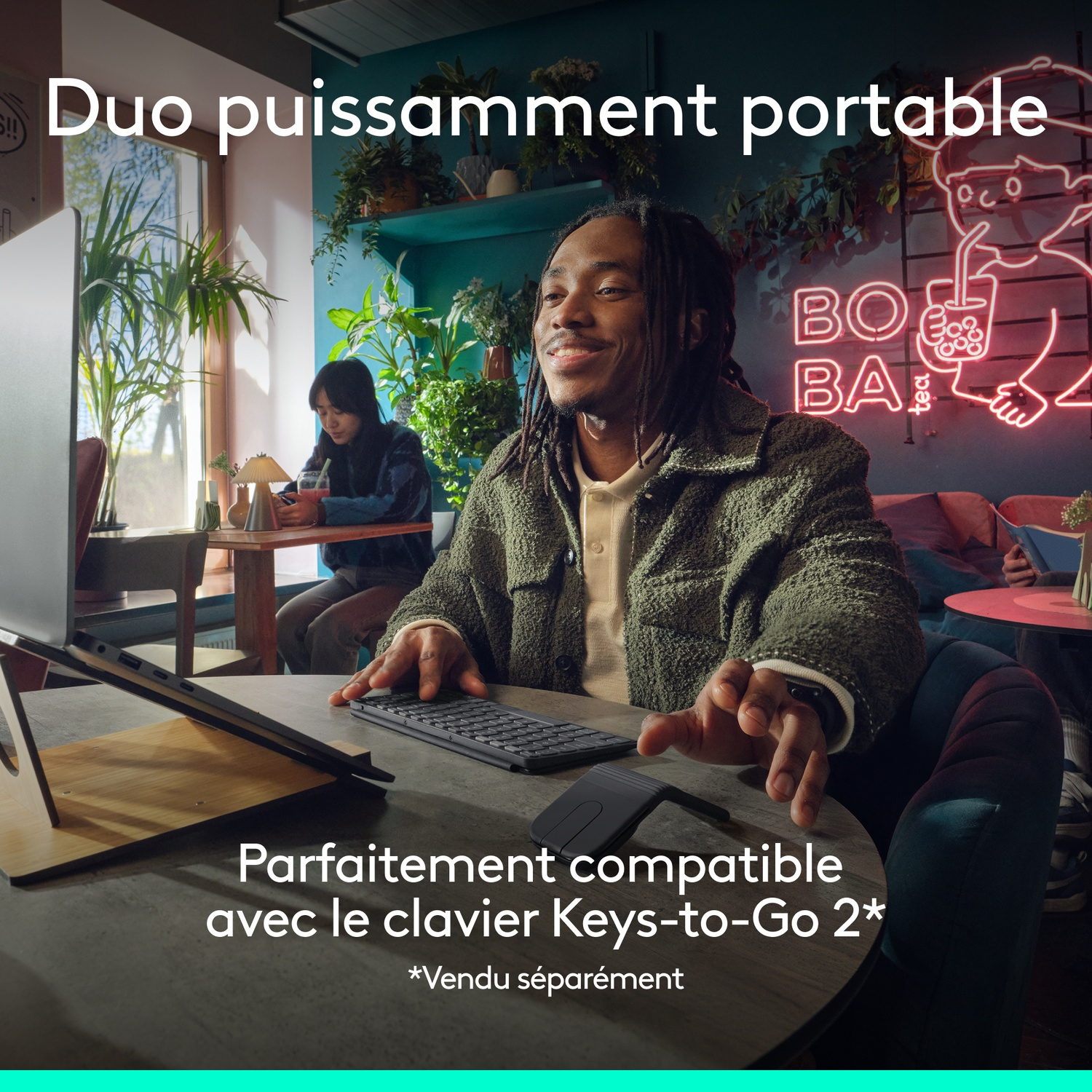 Homme dans un café avec ordinateur portable et clavier. Néon au fond.