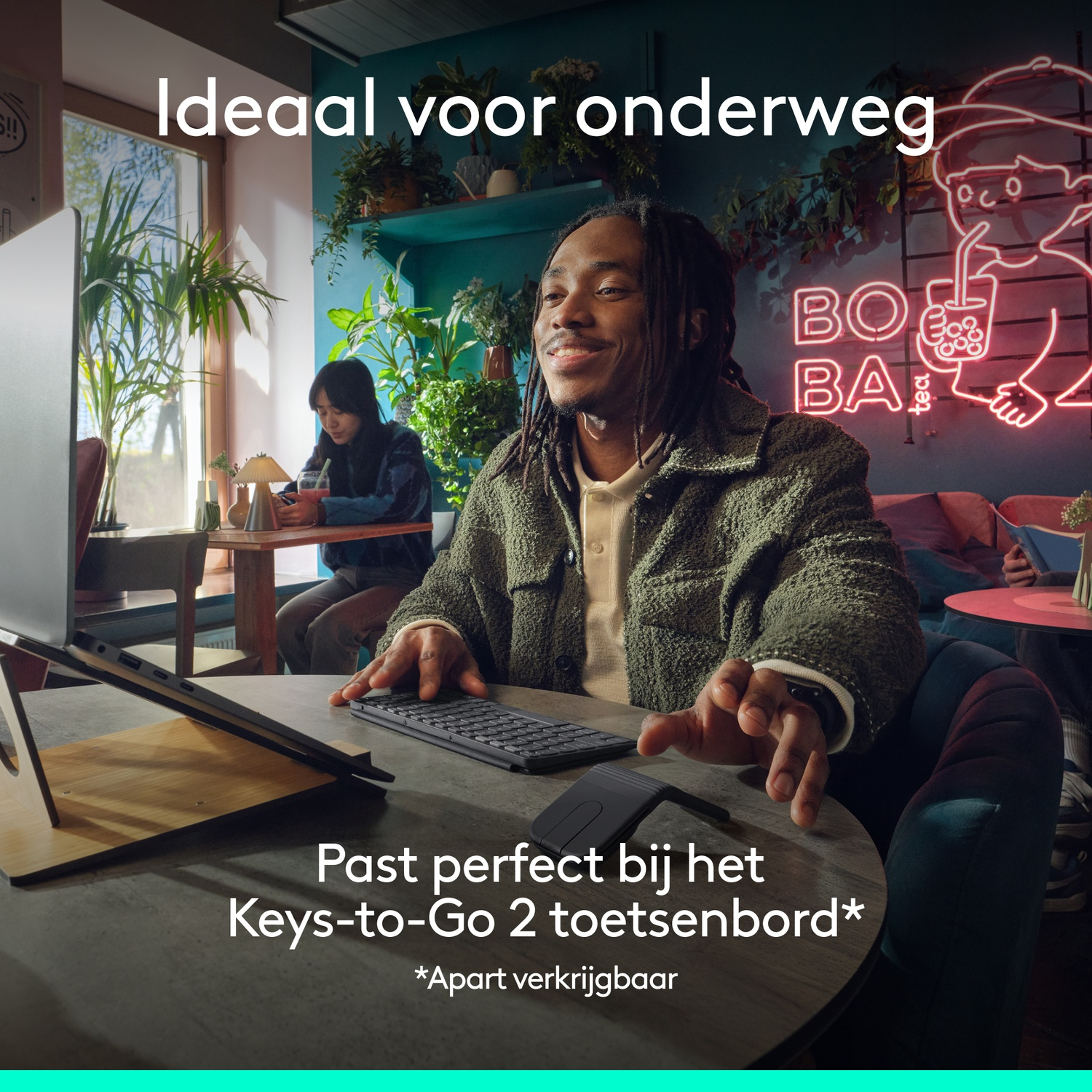 Man met dreadlocks in een café, toetsenbord en laptop op tafel.