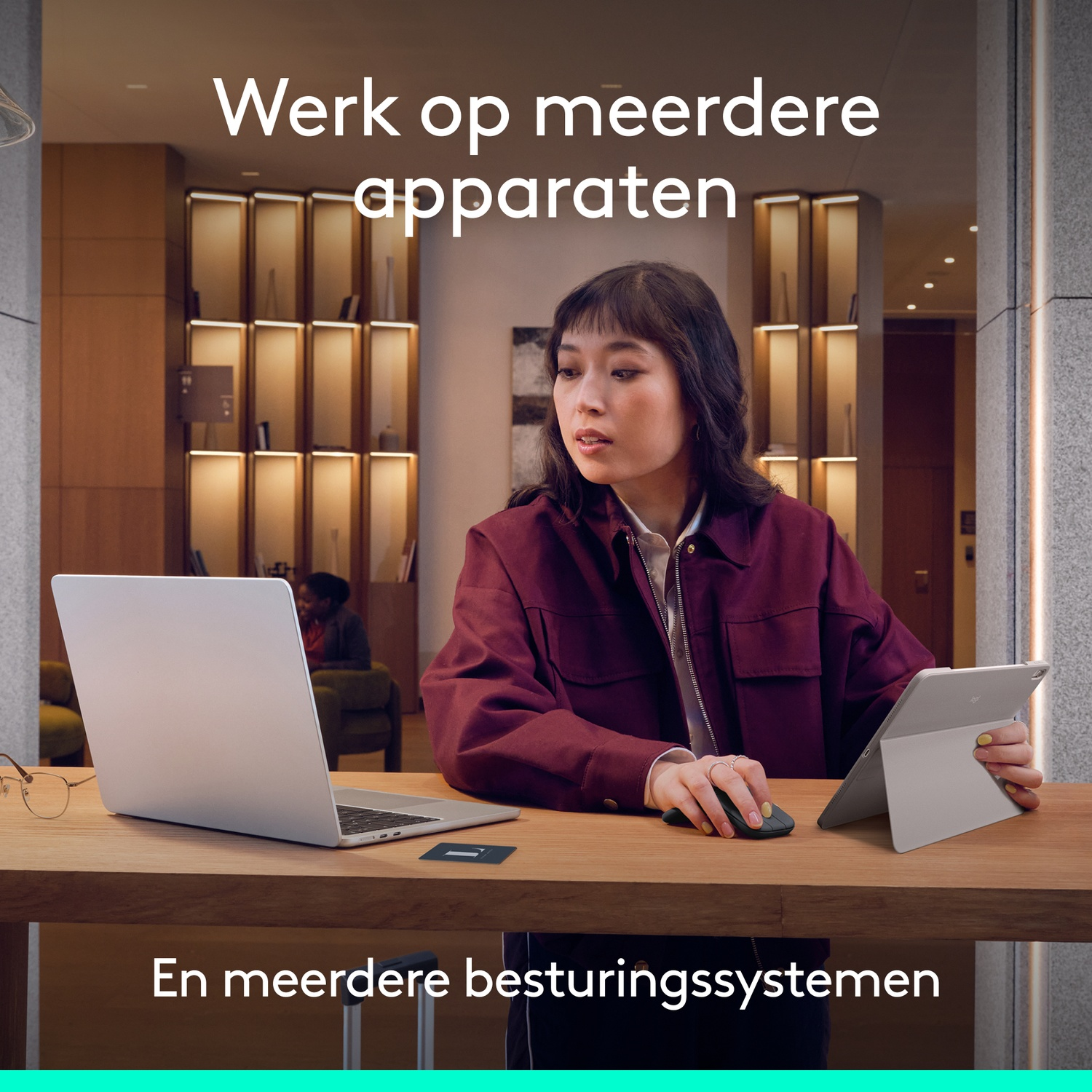 Een vrouw gebruikt een laptop, tablet en muis aan een houten bureau.