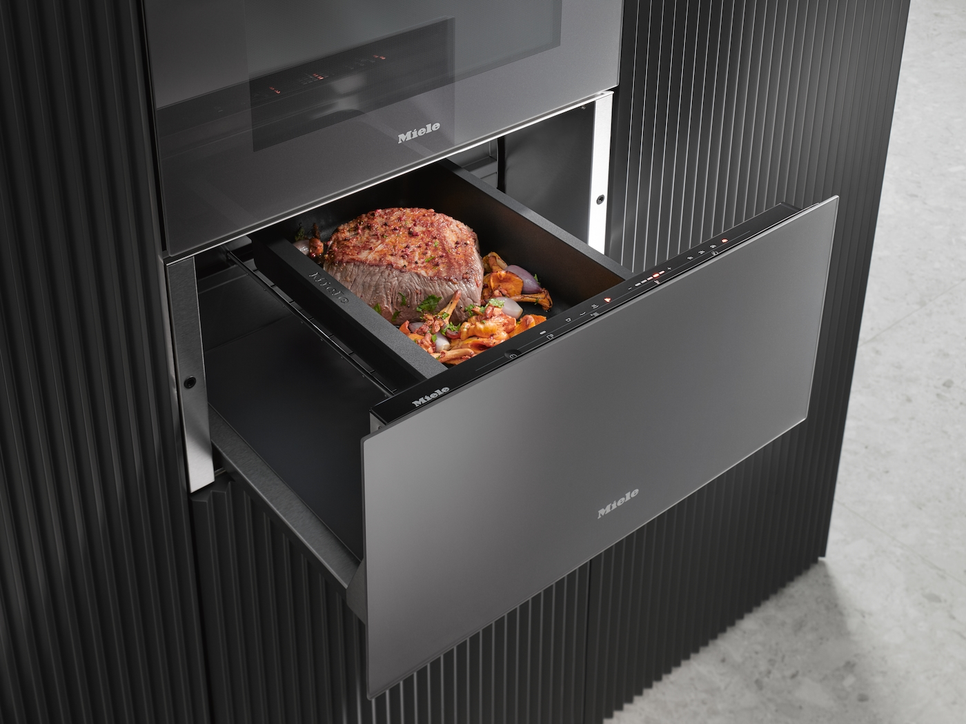Ein Braten mit Gemüse in einer Schublade eines Miele-Ofens.