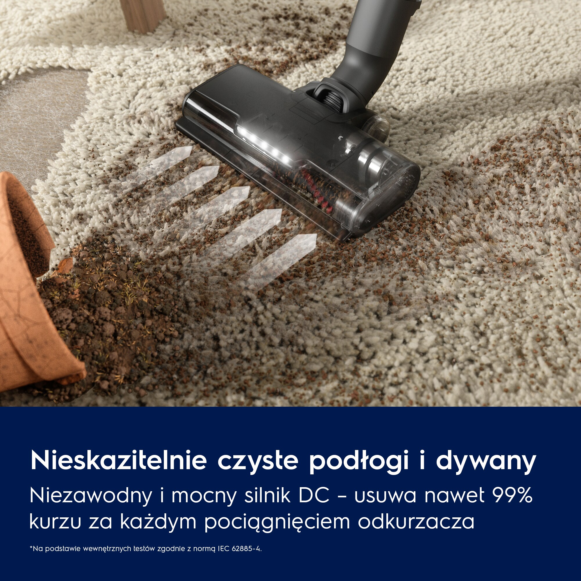 Odkurzacz czyści brudny dywan. Obok leży przewrócona doniczka.