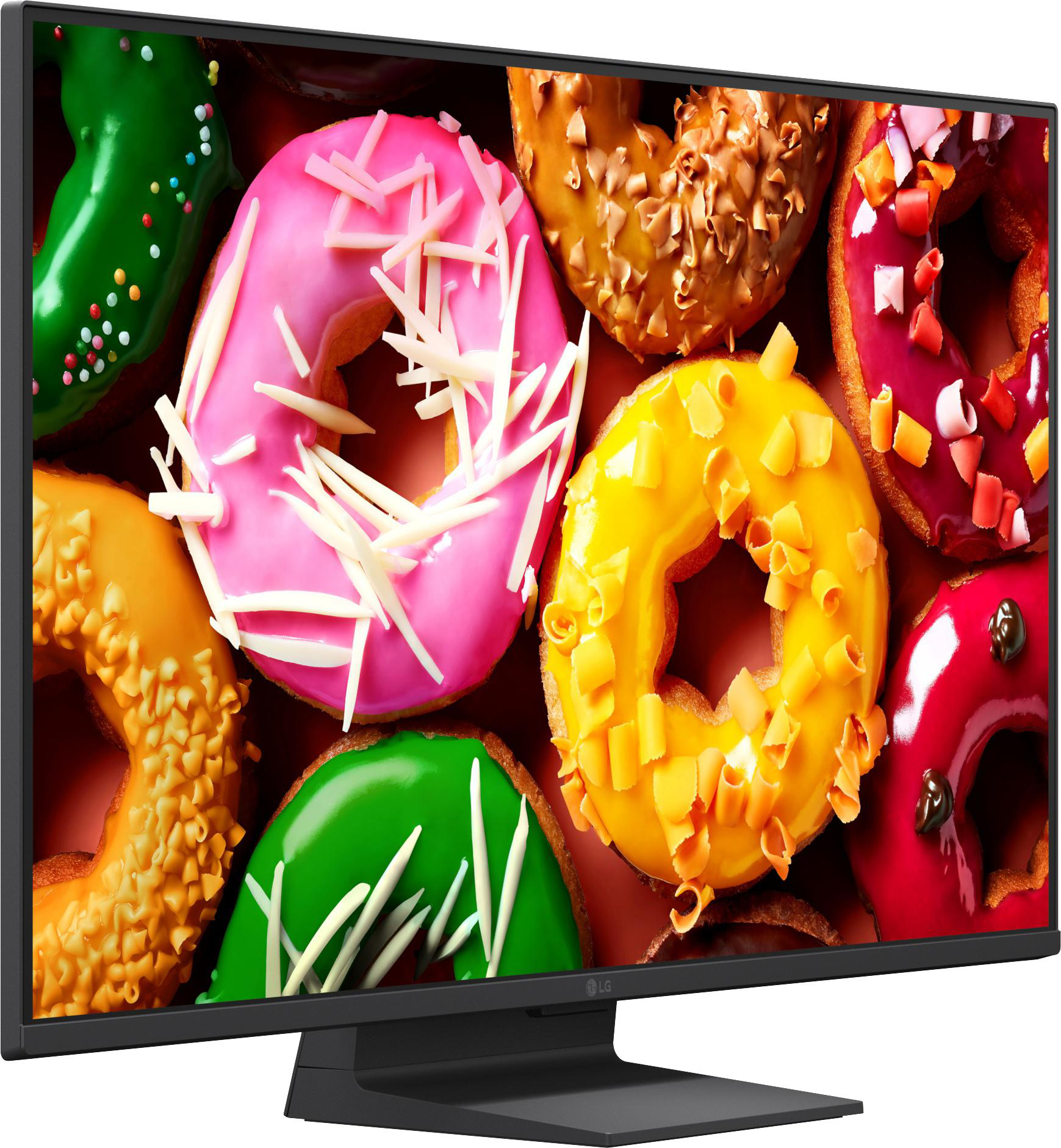 Ein Monitor zeigt ein Nahaufnahmebild von bunten, glasierten Donuts mit Streuseln und Zuckerguss.