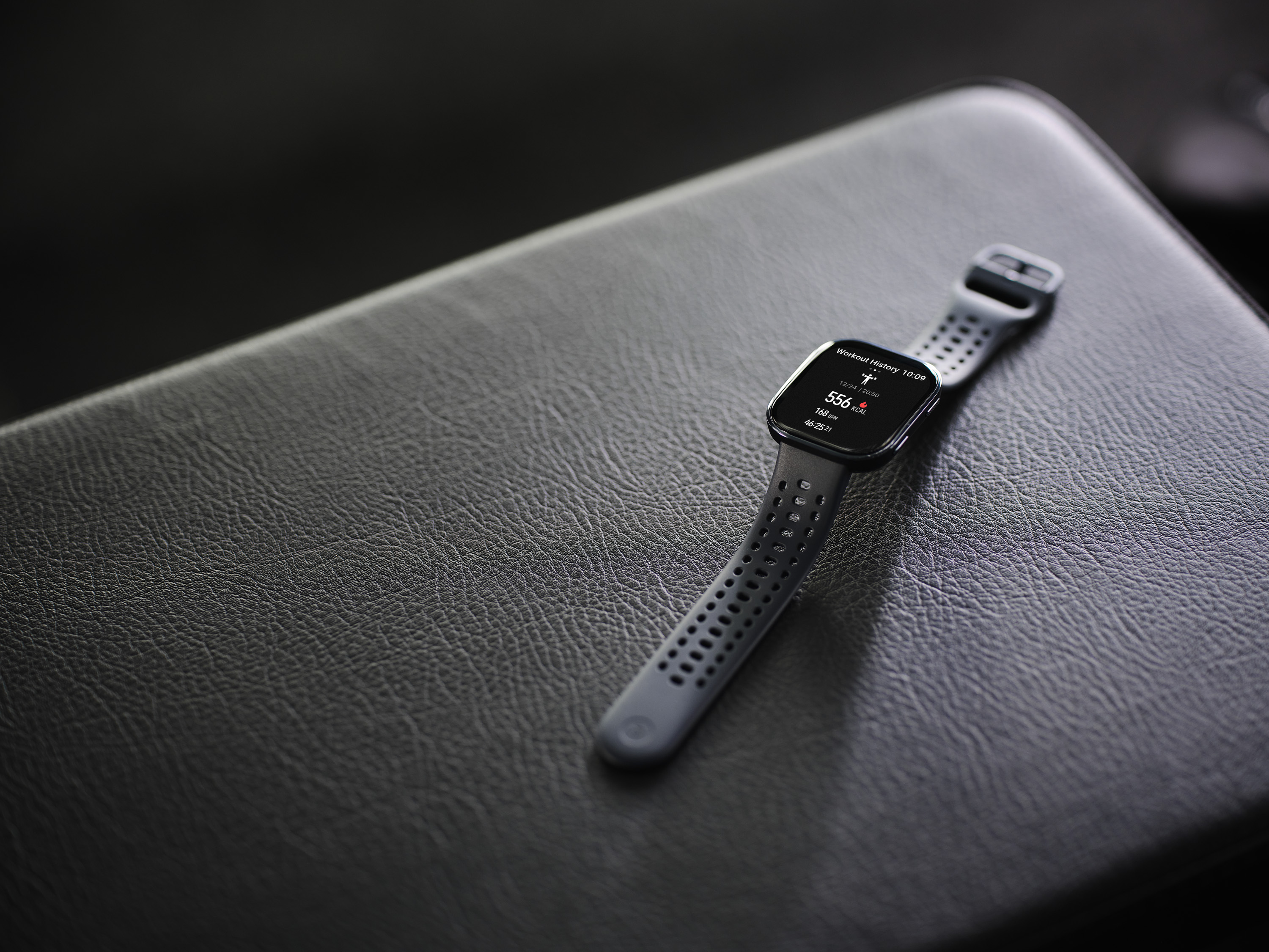 Szary smartwatch z historią treningów na czarnej skórze.