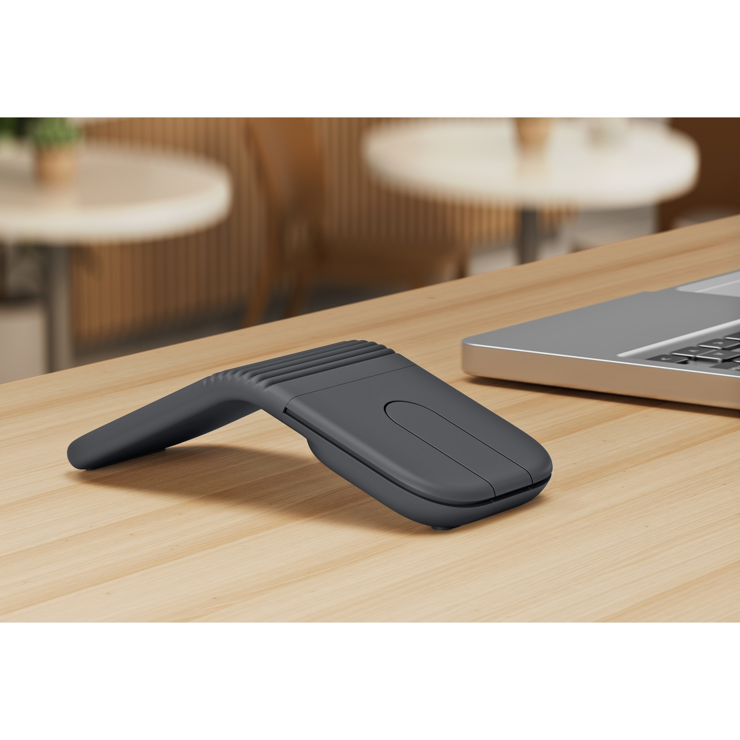 Mouse pieghevole grigio scuro accanto a un laptop su una scrivania di legno.