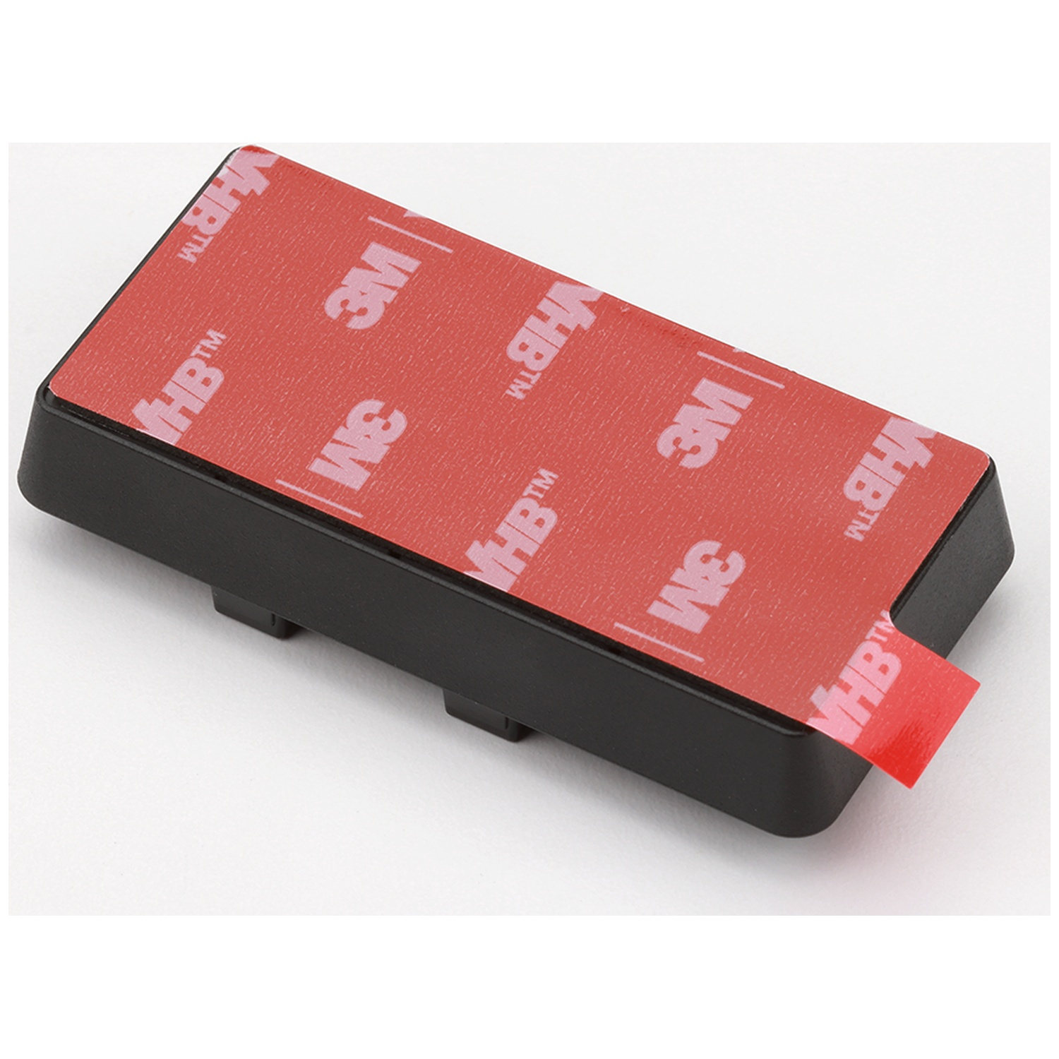 Objet rectangulaire noir avec ruban adhésif rouge 3M VHB sur le dessus, avec languette rouge.
