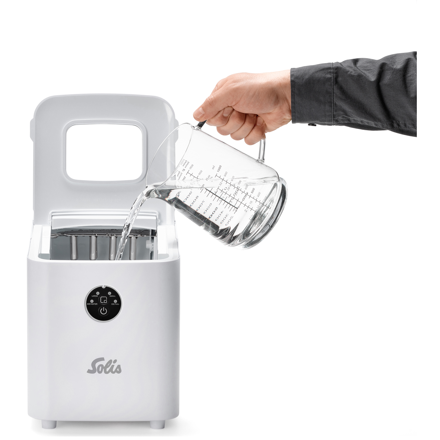 Een hand giet water uit een maatbeker in een witte Solis ijsmachine.