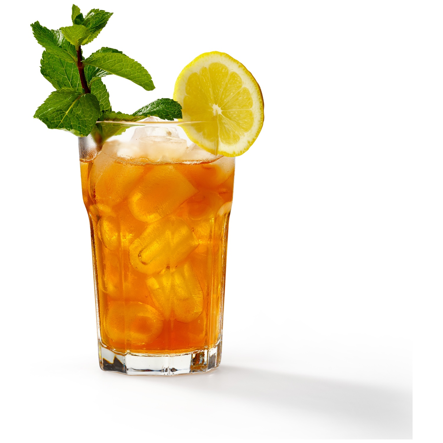 Un verre de thé glacé avec glaçons, citron et menthe sur fond blanc.