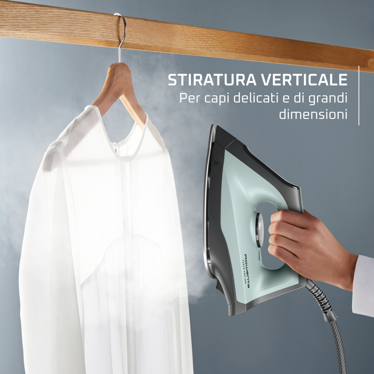 Una persona stira una camicia bianca verticalmente con un ferro da stiro a vapore.
