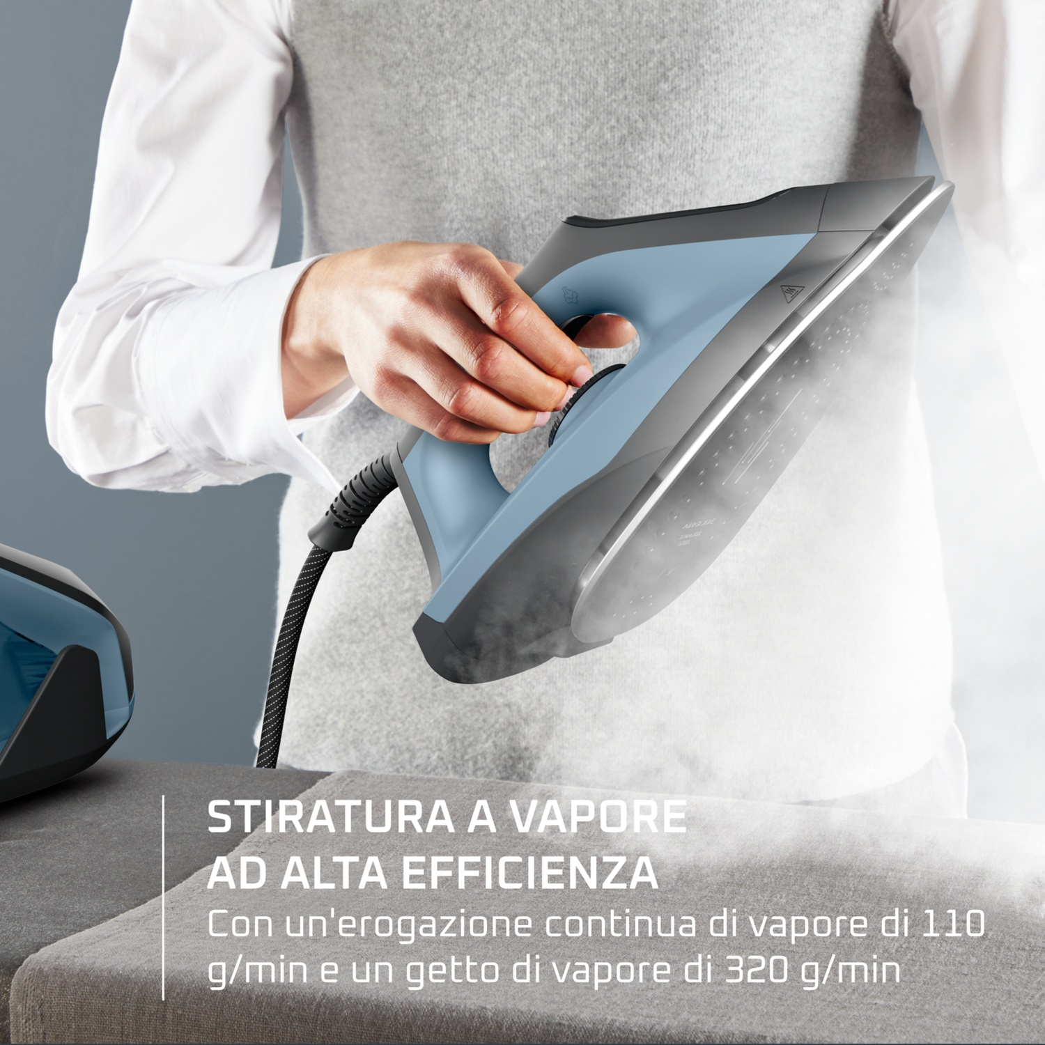 Una persona stira con un ferro da stiro a vapore blu. Il vapore sale.