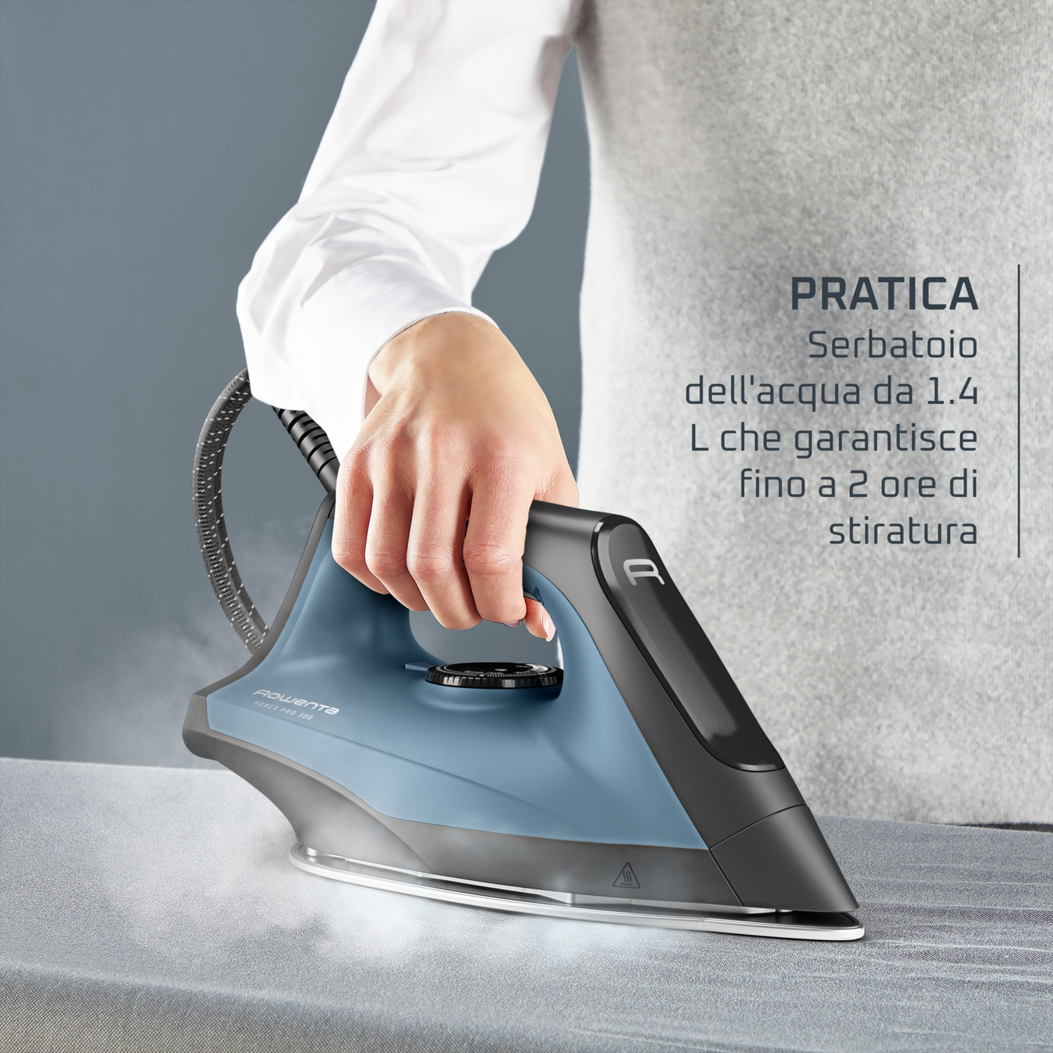 Una mano tiene un ferro da stiro a vapore blu, spruzzando vapore su tessuto grigio.