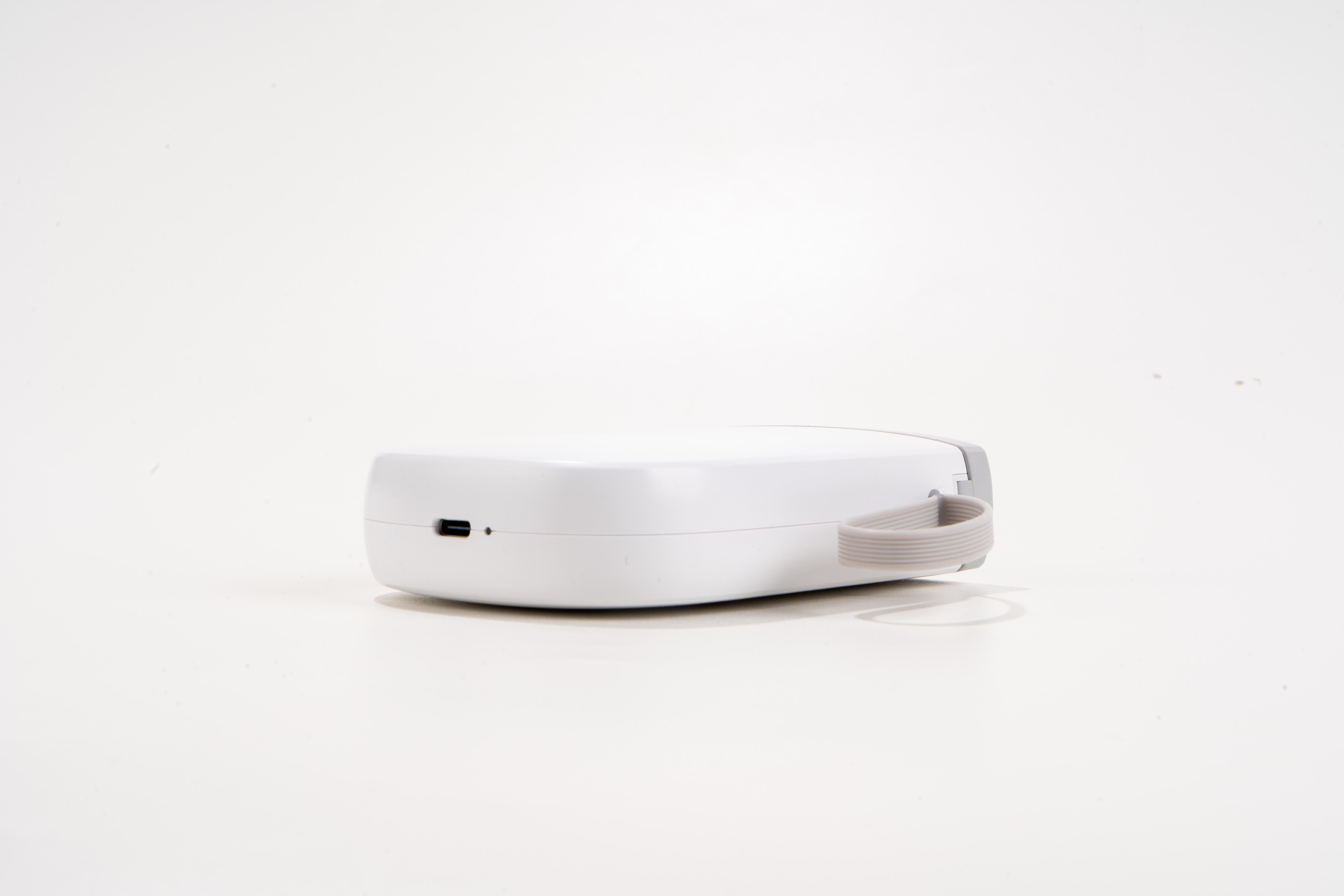 Ein weißes, rechteckiges Gerät mit einem USB-C-Anschluss und einem grauen Tragegriff.