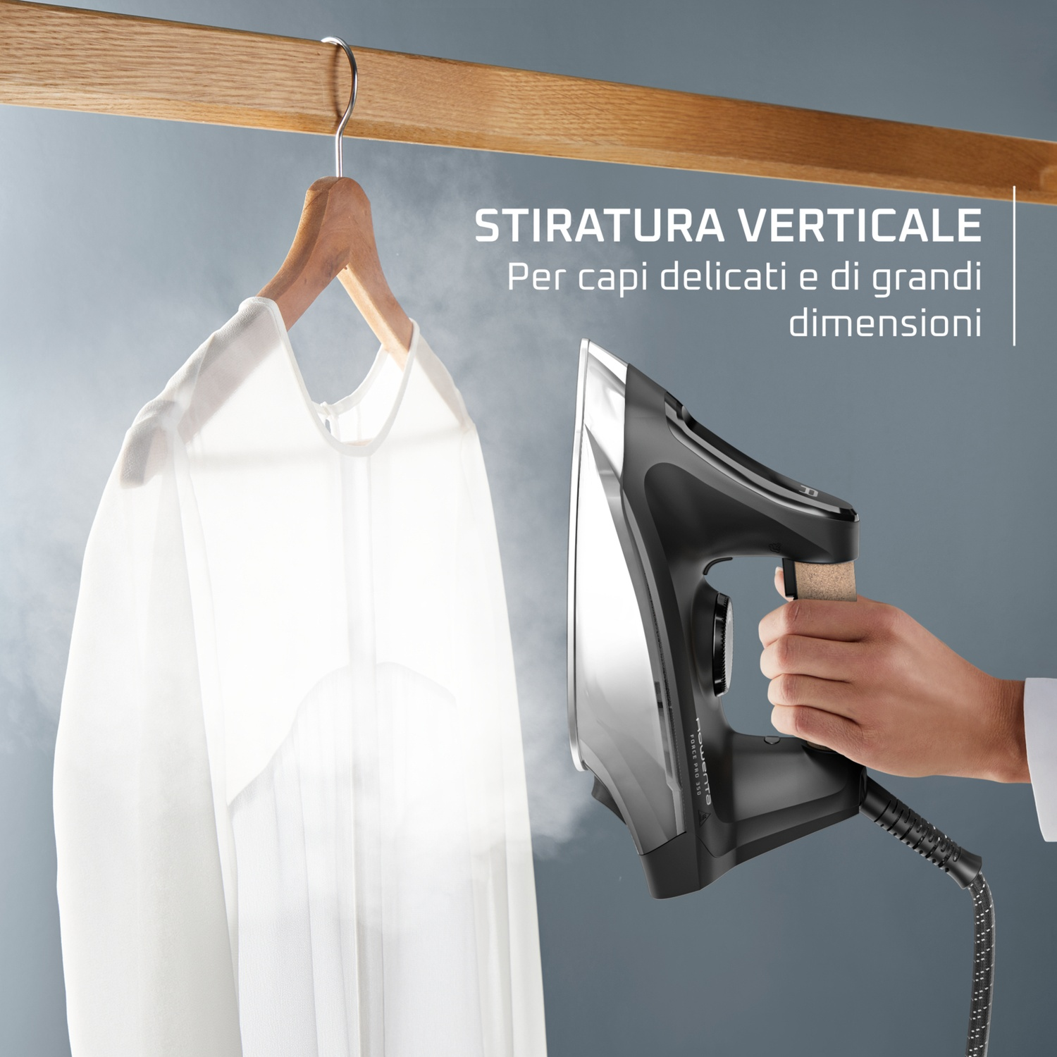 Una mano tiene un ferro da stiro a vapore accanto a una camicia bianca.