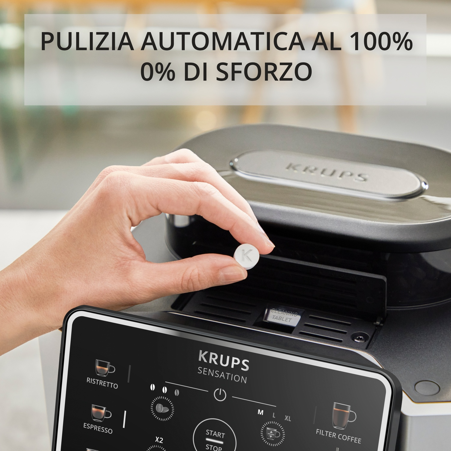 Una mano inserisce una pastiglia per la pulizia in una macchina da caffè KRUPS. Il display mostra opzioni.