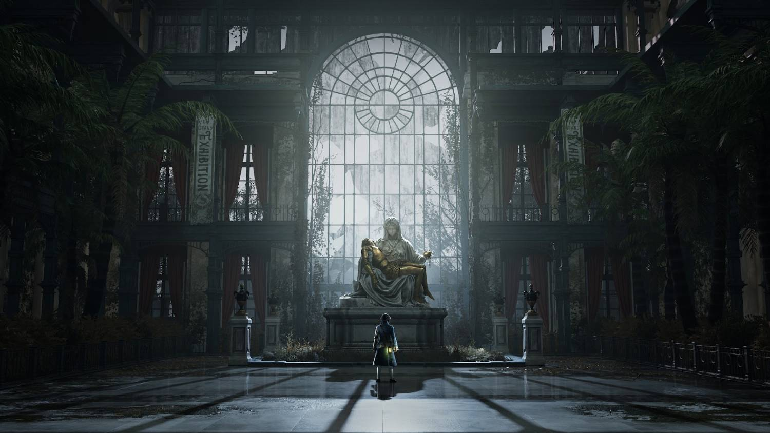 Una persona se para ante una estatua bajo un gran techo de cristal en un edificio abandonado.