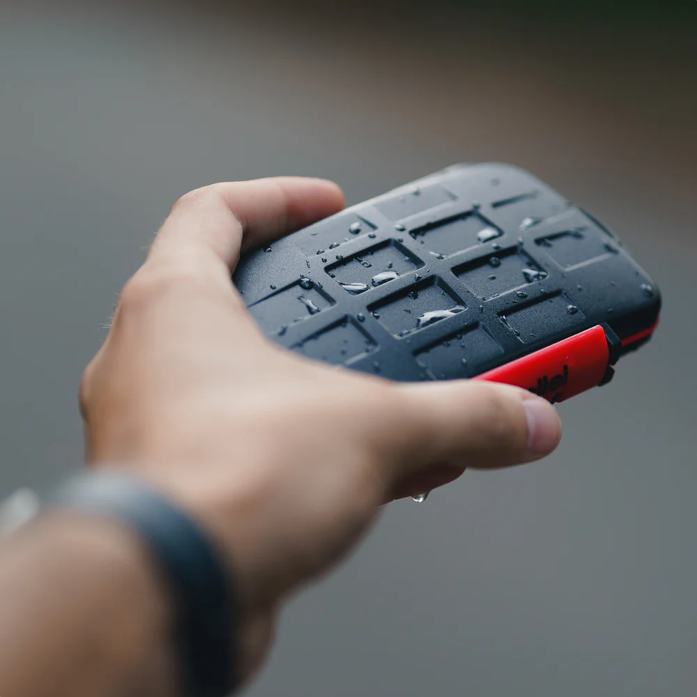 Une main tient un disque externe noir éclaboussé d'eau avec un accent rouge.