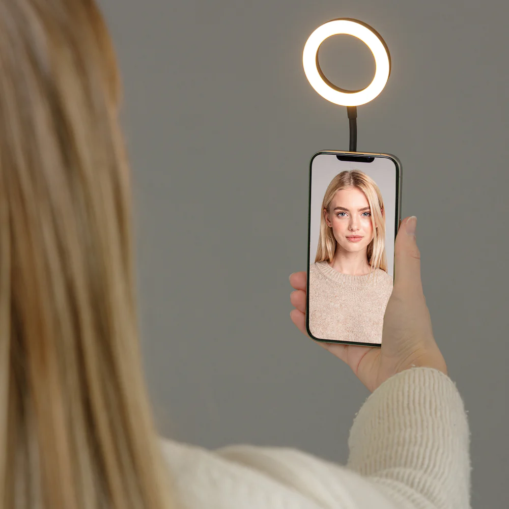 Una donna tiene uno smartphone con un ritratto e un anello luminoso.