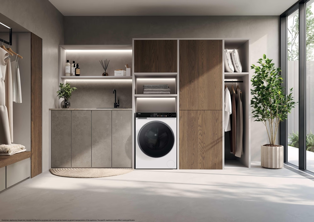 Modernes Waschküchen-Design mit weißer Waschmaschine, Spüle, Regalen und Kleidung.