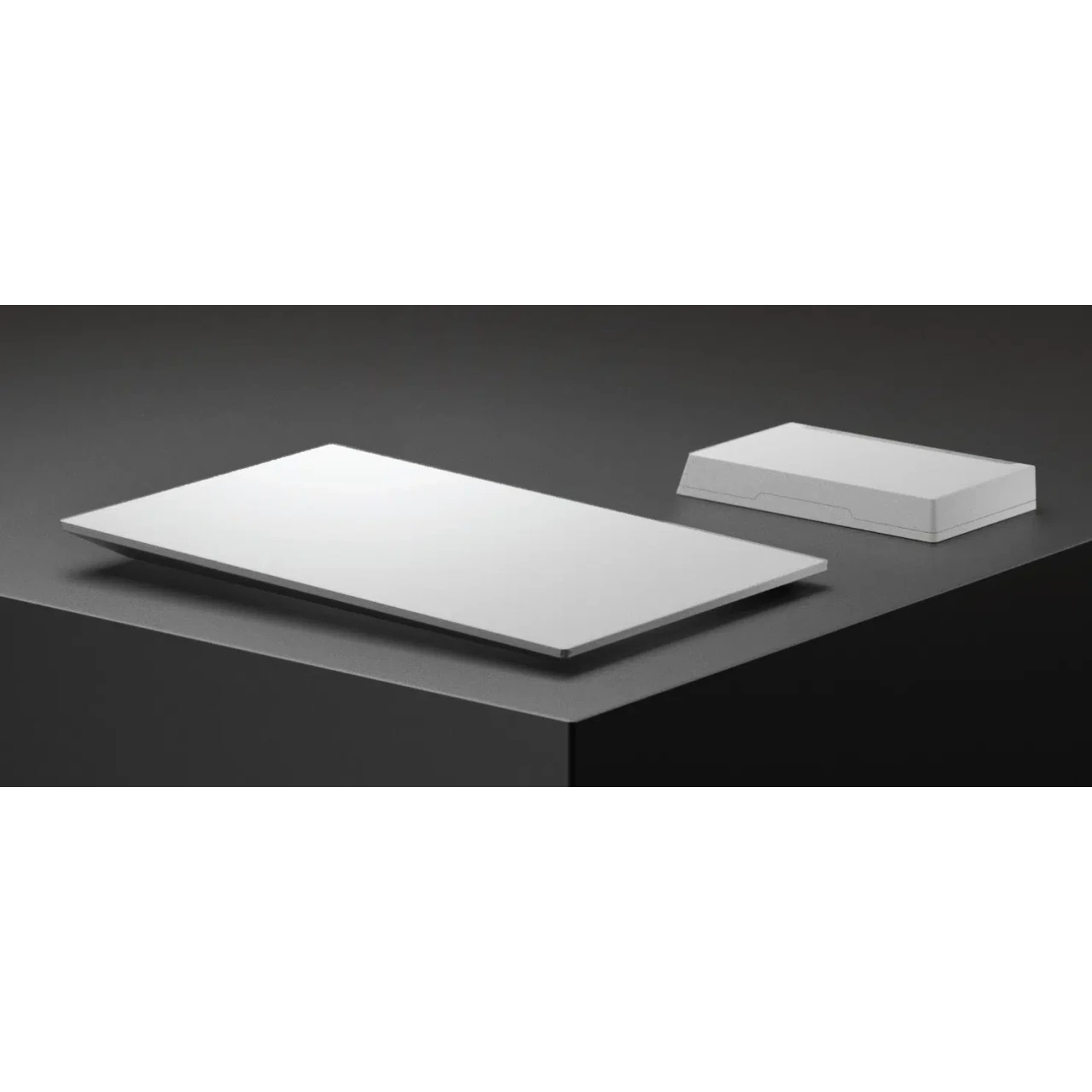 Deux objets rectangulaires blancs sur fond noir. L'un plat, l'autre avec un couvercle.