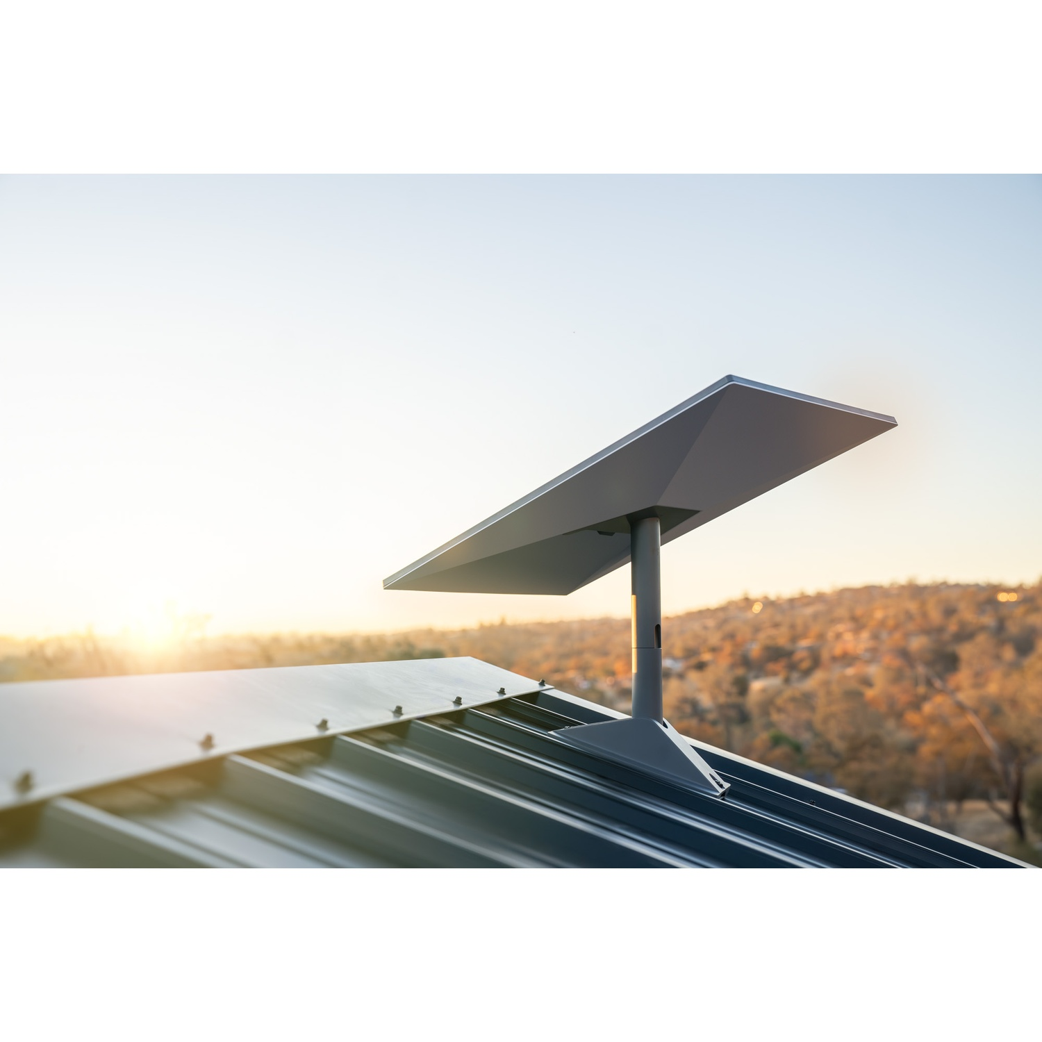 Een schotelantenne op een dak bij zonsondergang.