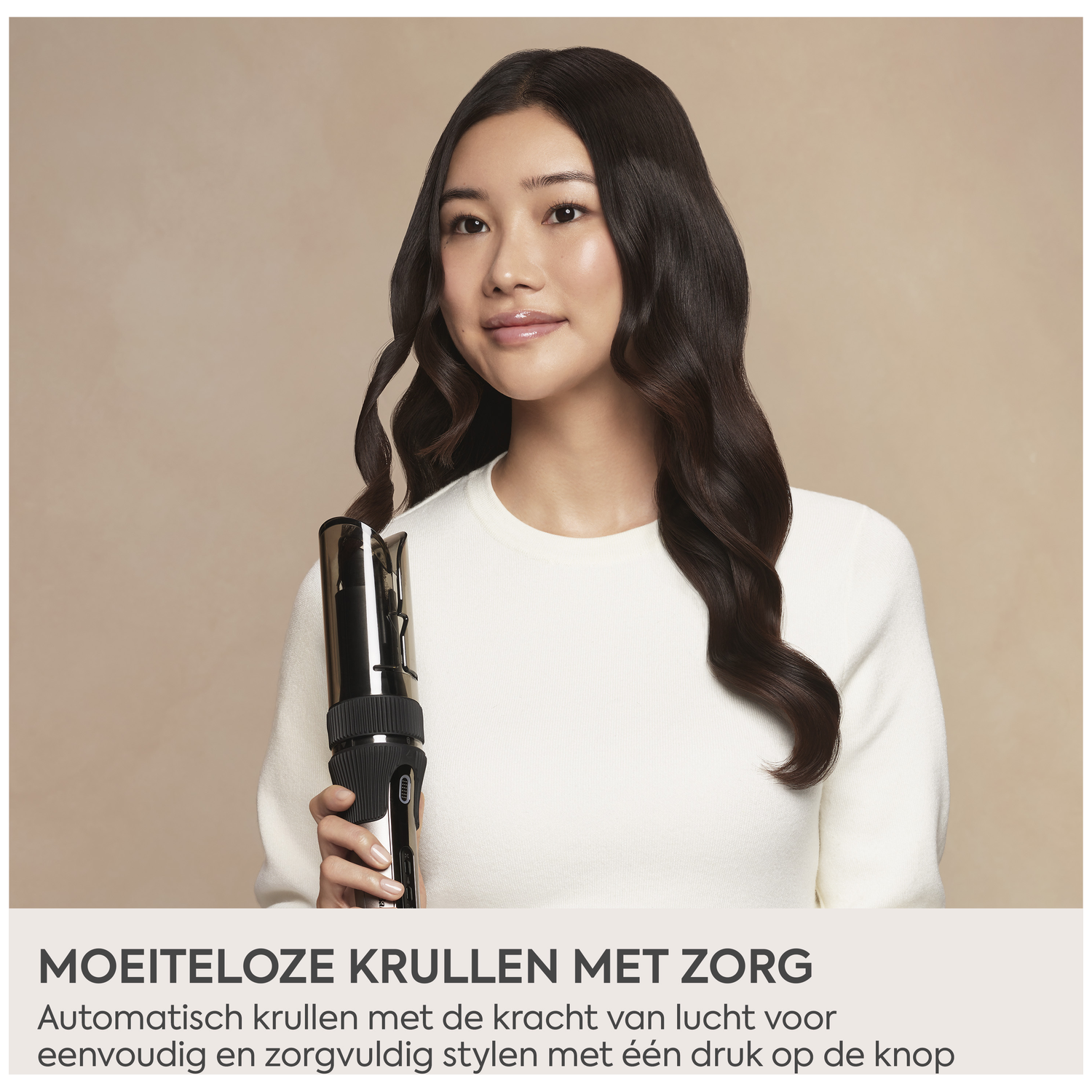 Een jonge vrouw houdt een automatische krultang vast, haar haar is donker en golvend.