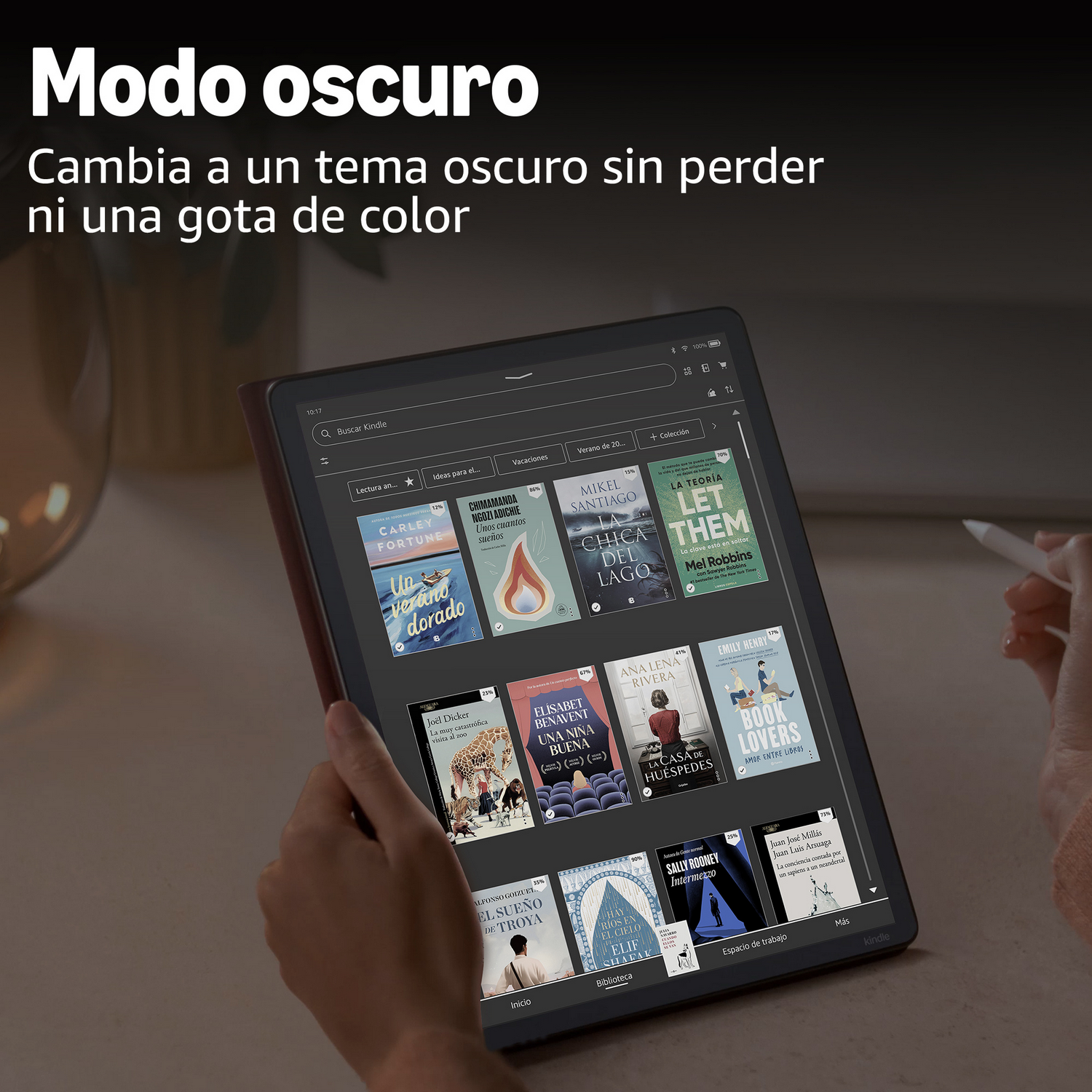 Una persona sostiene una tablet Kindle mostrando portadas de libros. El texto "Modo oscuro" es prominente.