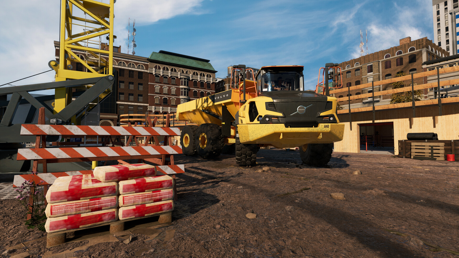 Ein gelber Volvo-Muldenkipper steht auf einer Baustelle mit einem Kran und Gebäuden im Hintergrund.
