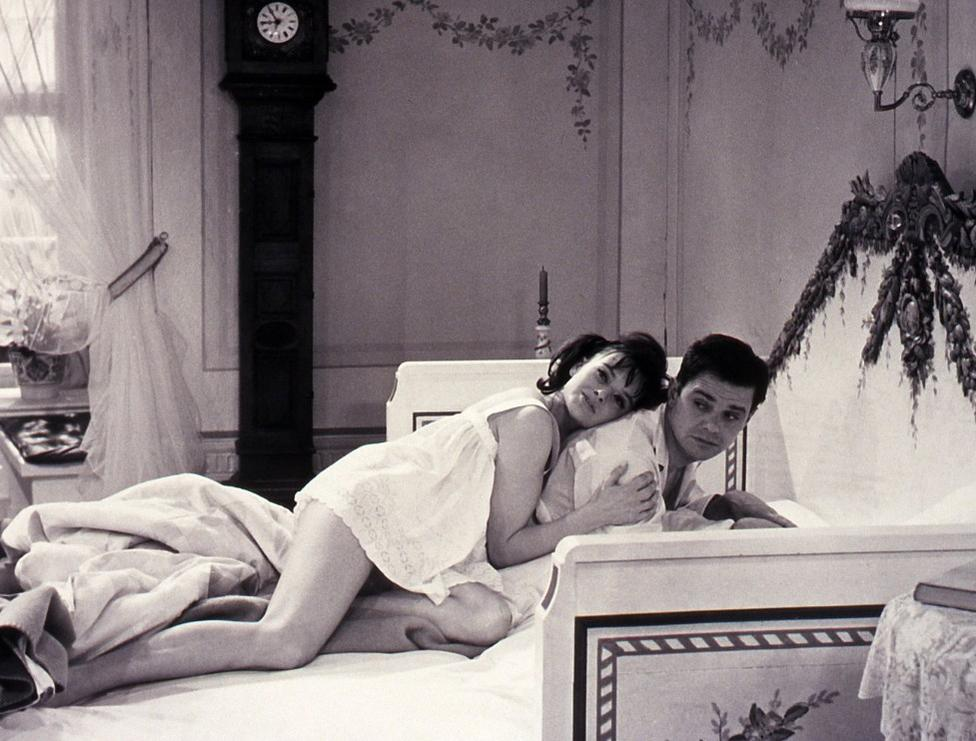 Ein Mann und eine Frau liegen in einem Bett, sie lehnt ihren Kopf an ihn.