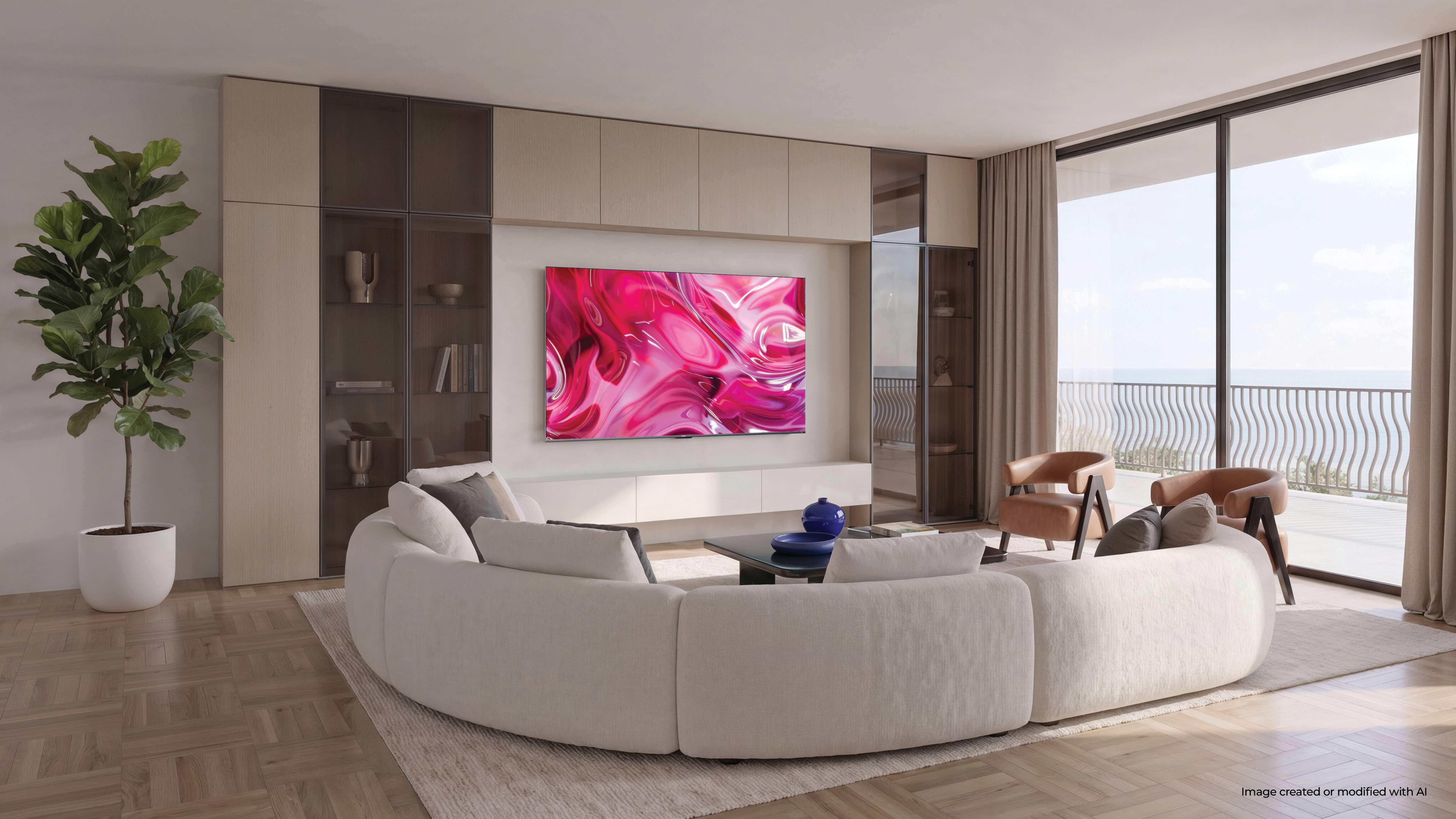 Sala de estar moderna con sofá curvo, TV con arte abstracto, dos sillones y vista al mar.