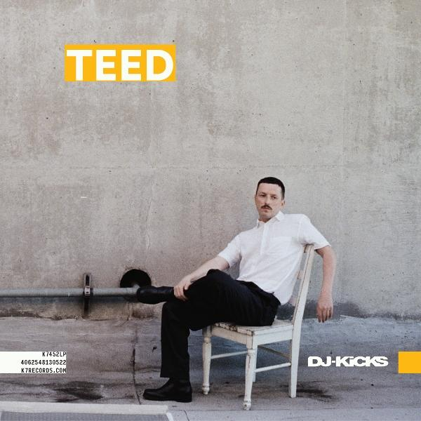 Mann in weißem Hemd sitzt auf Stuhl vor Betonwand, TEED Schriftzug.