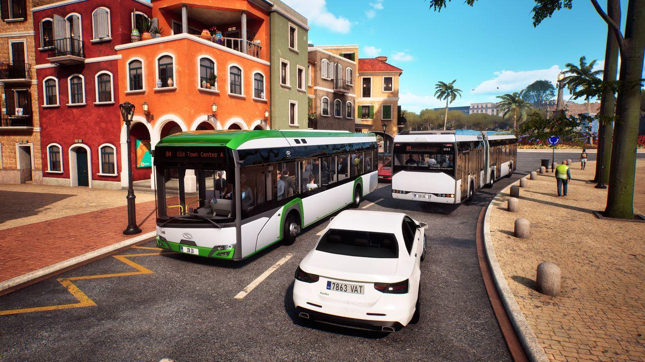 Weiße Limousine und Busse auf einer Straße vor bunten Gebäuden und Palmen.