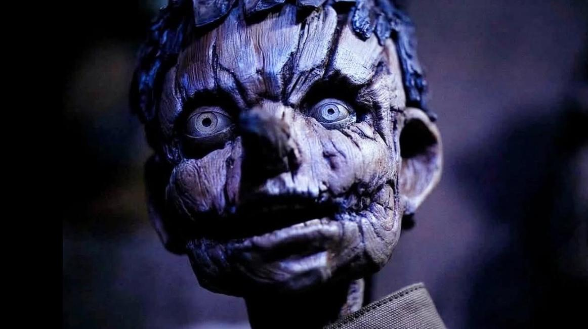 Nahaufnahme eines unheimlichen Puppengesichts mit blauen Augen und zerfurchter Haut.
