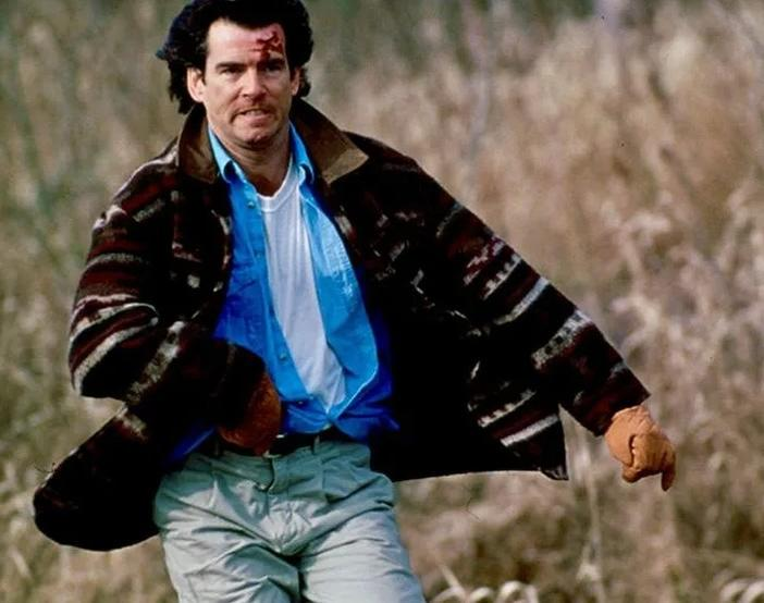 Mann mit blauer Hemd, brauner Jacke, läuft im Feld mit Wunden im Gesicht.