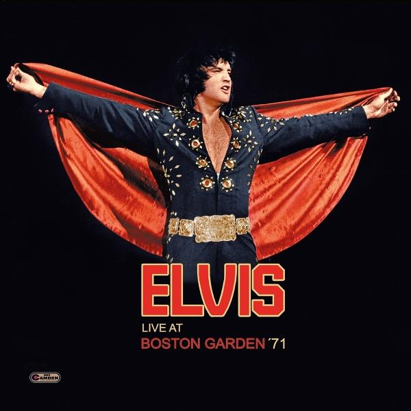 Elvis Presley in einem dunklen Anzug mit roten Umhang und goldenem Gürtel.